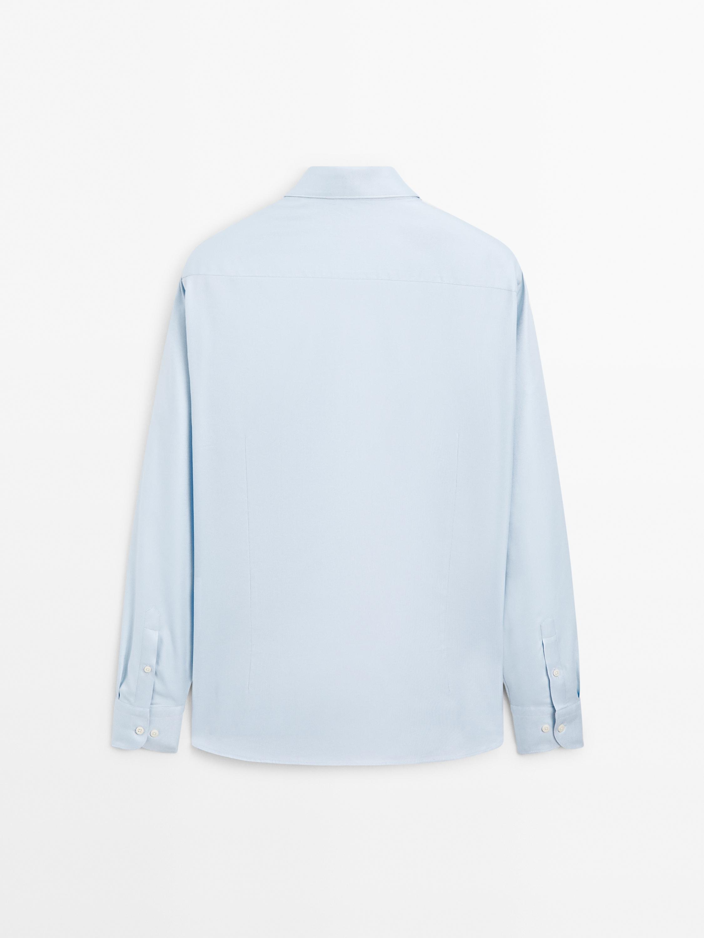 Vista posteriore di camicia azzurro chiaro con colletto classico e maniche lunghe con polsini abbottonati.