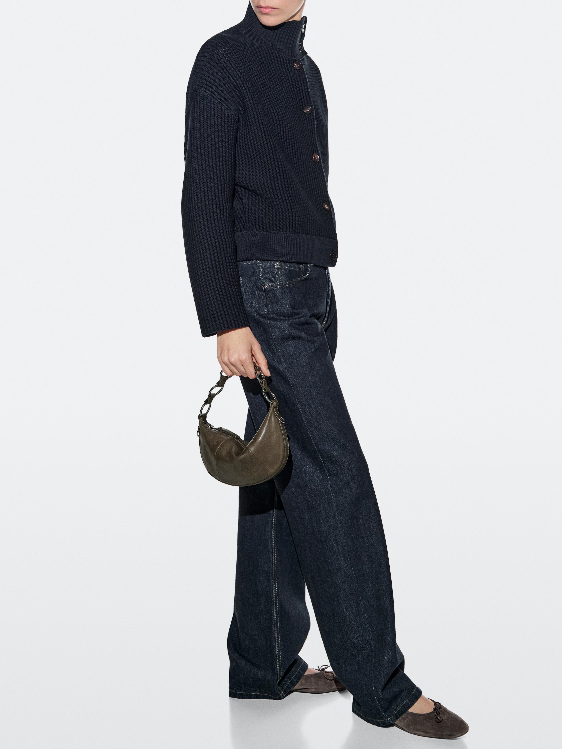 Black knitted jacket set with buttons, dark wide-leg jeans, and a small khaki bag.