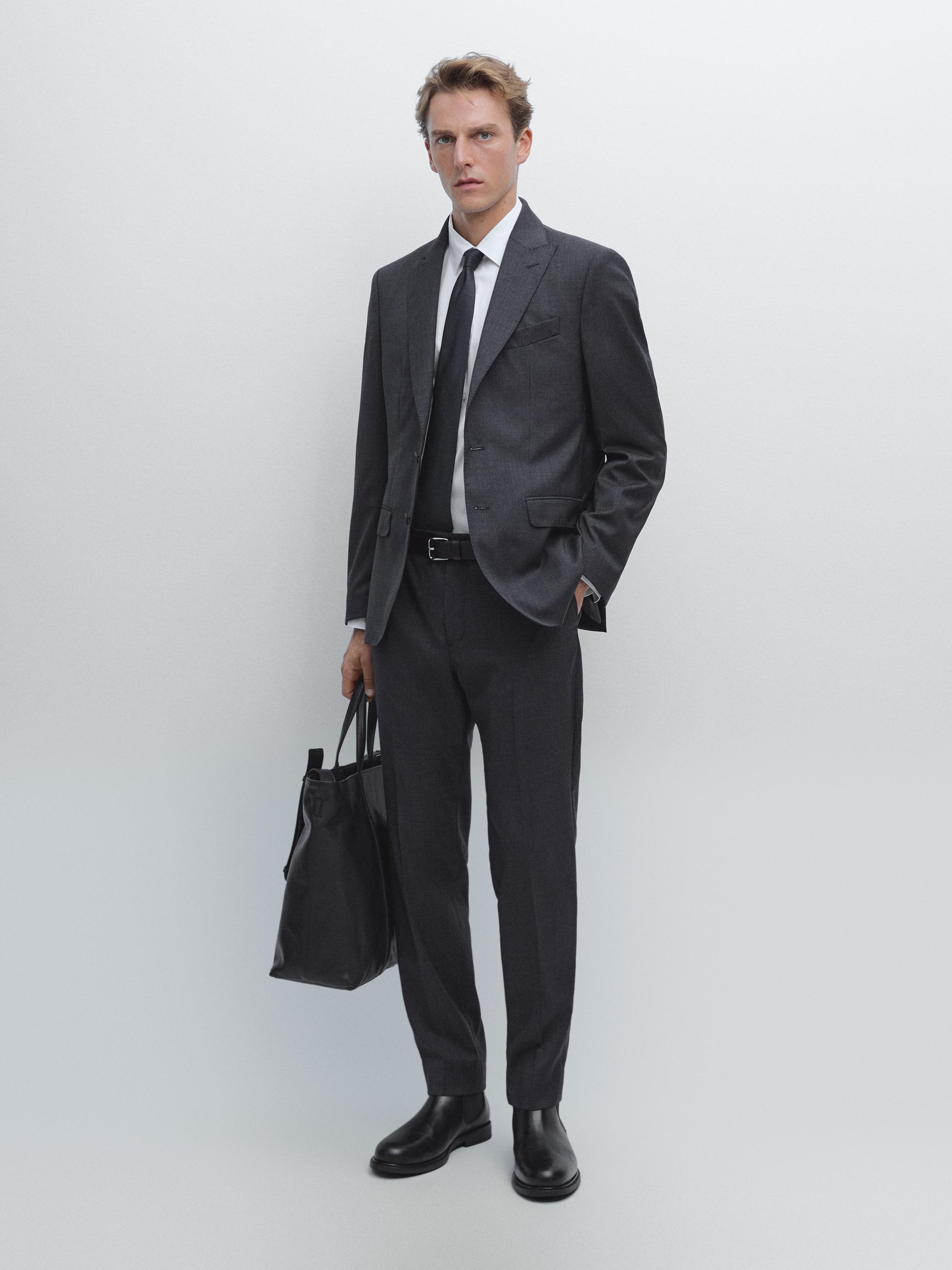 Ensemble de costume bleu marine avec veste, pantalon de tailleur, chemise blanche, cravate noire et chaussures noires.