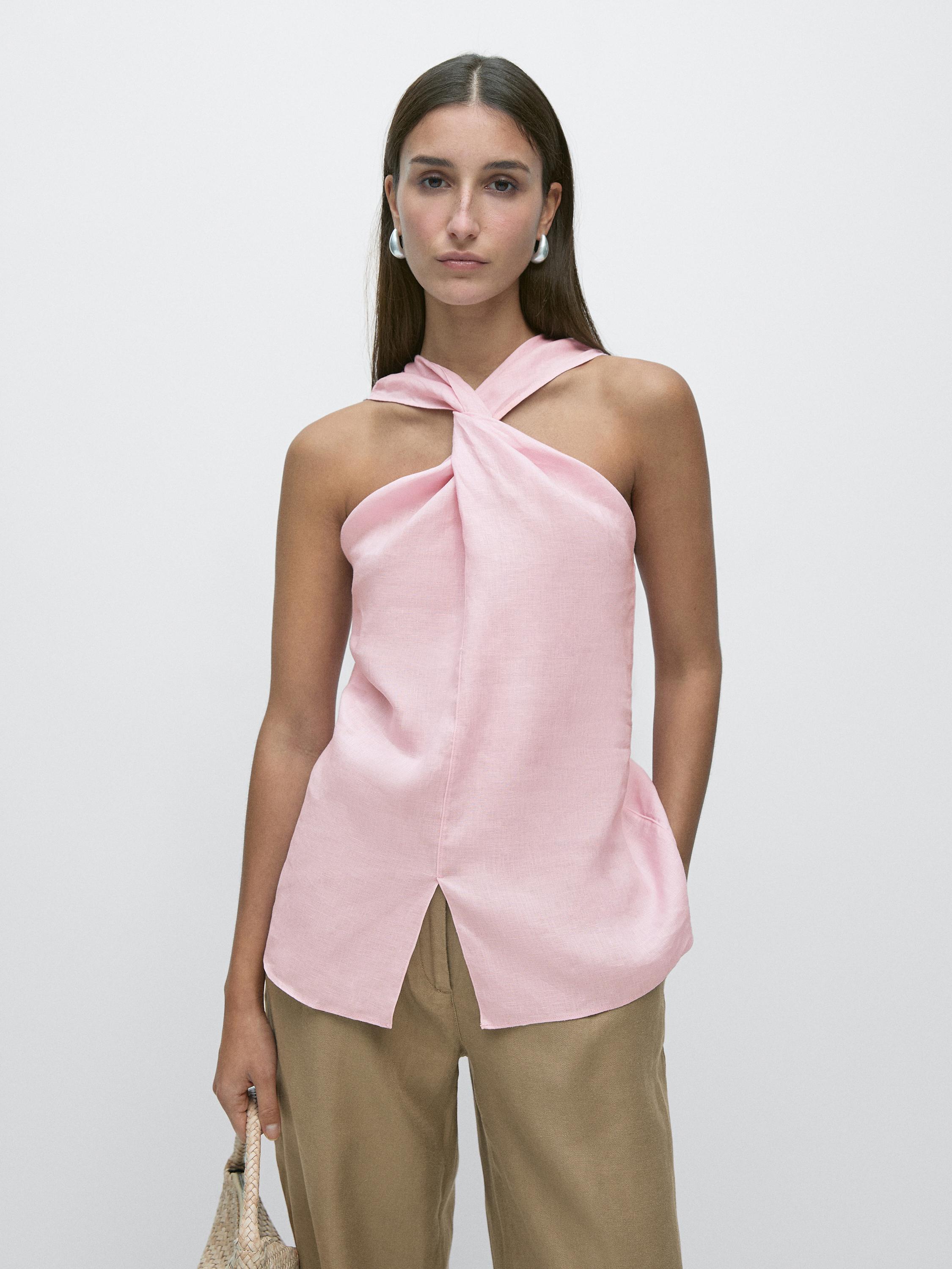 Conjunto de top rosa cruzado sin mangas y pantalones beige.