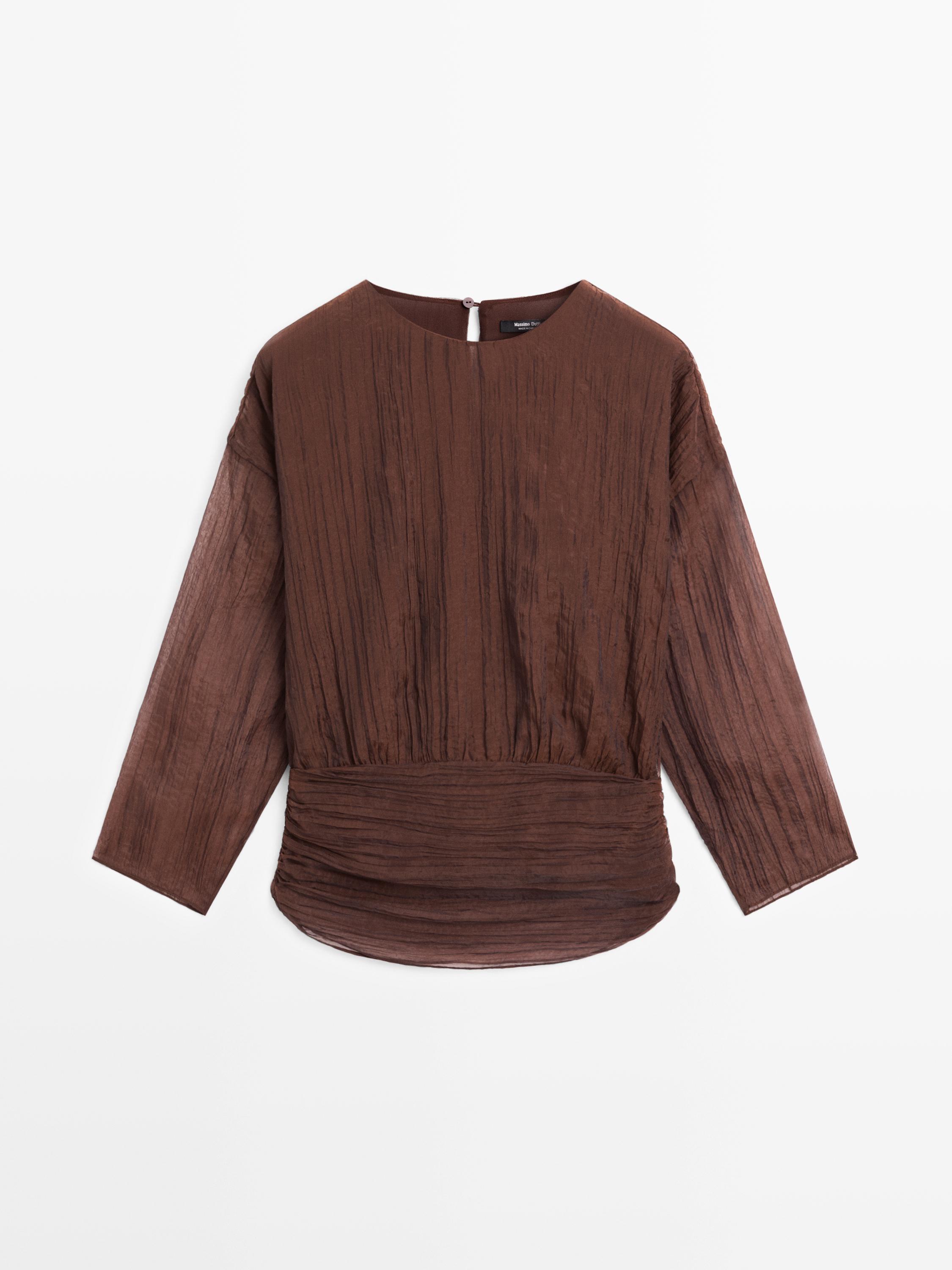 Front view of a caramel-colored blouse with a sash and ruched detail, long sleeves, and a back button closure.