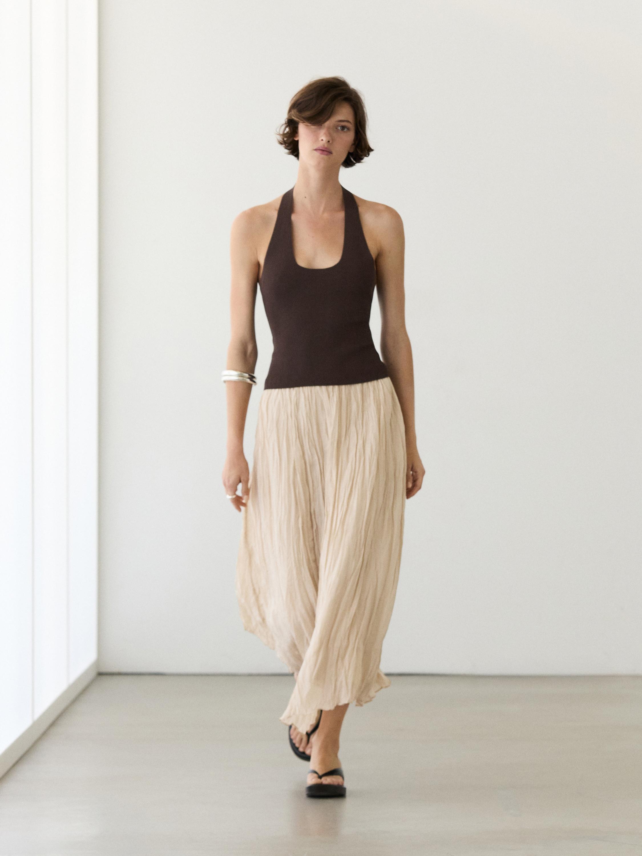 Conxunto de top marrón sen mangas e saia midi crua fluída con detalle engurrado.