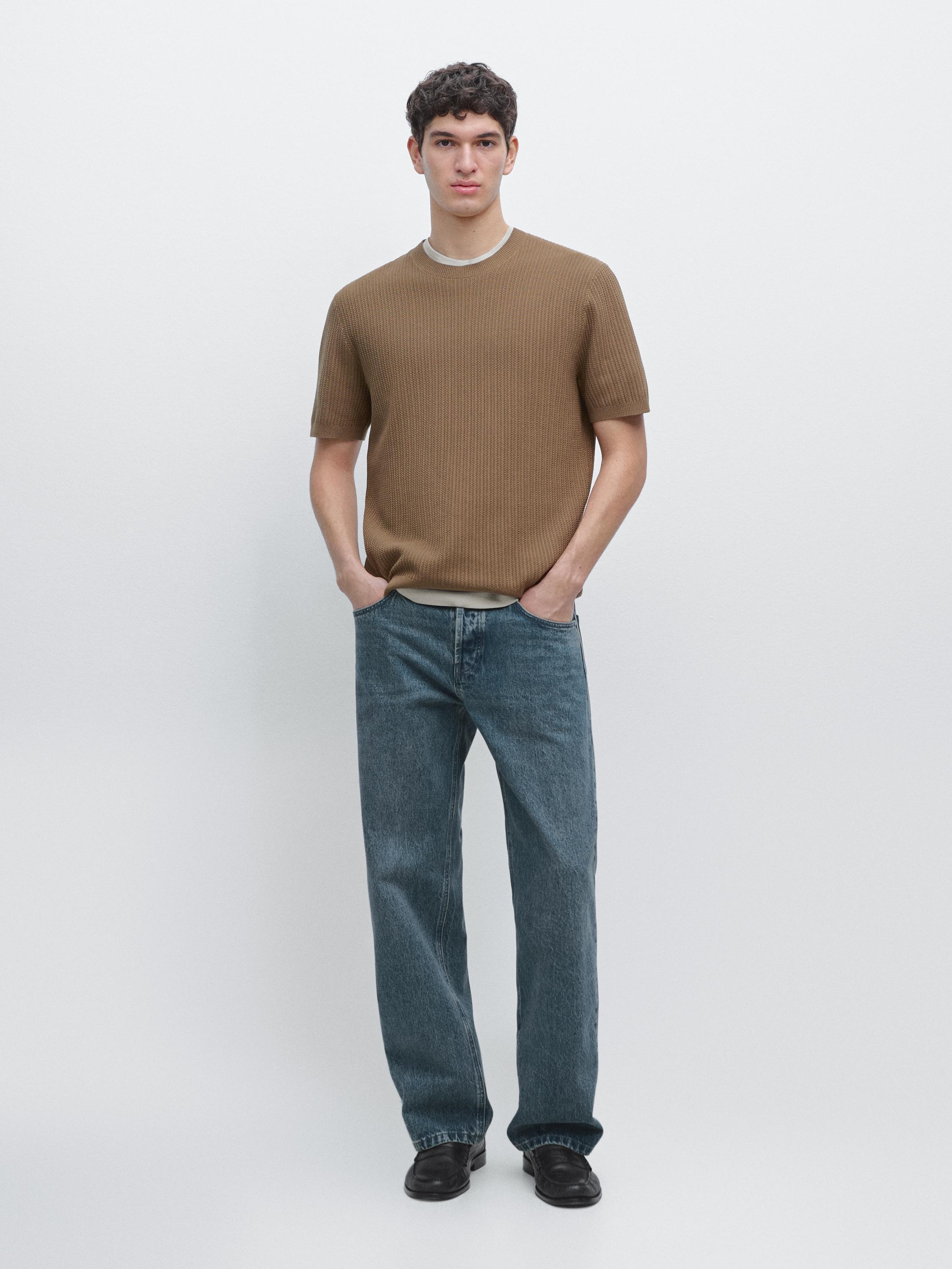 طقم يتكون من تي شيرت كاكي بأكمام قصيرة وبنطلون جينز أزرق مستقيم.