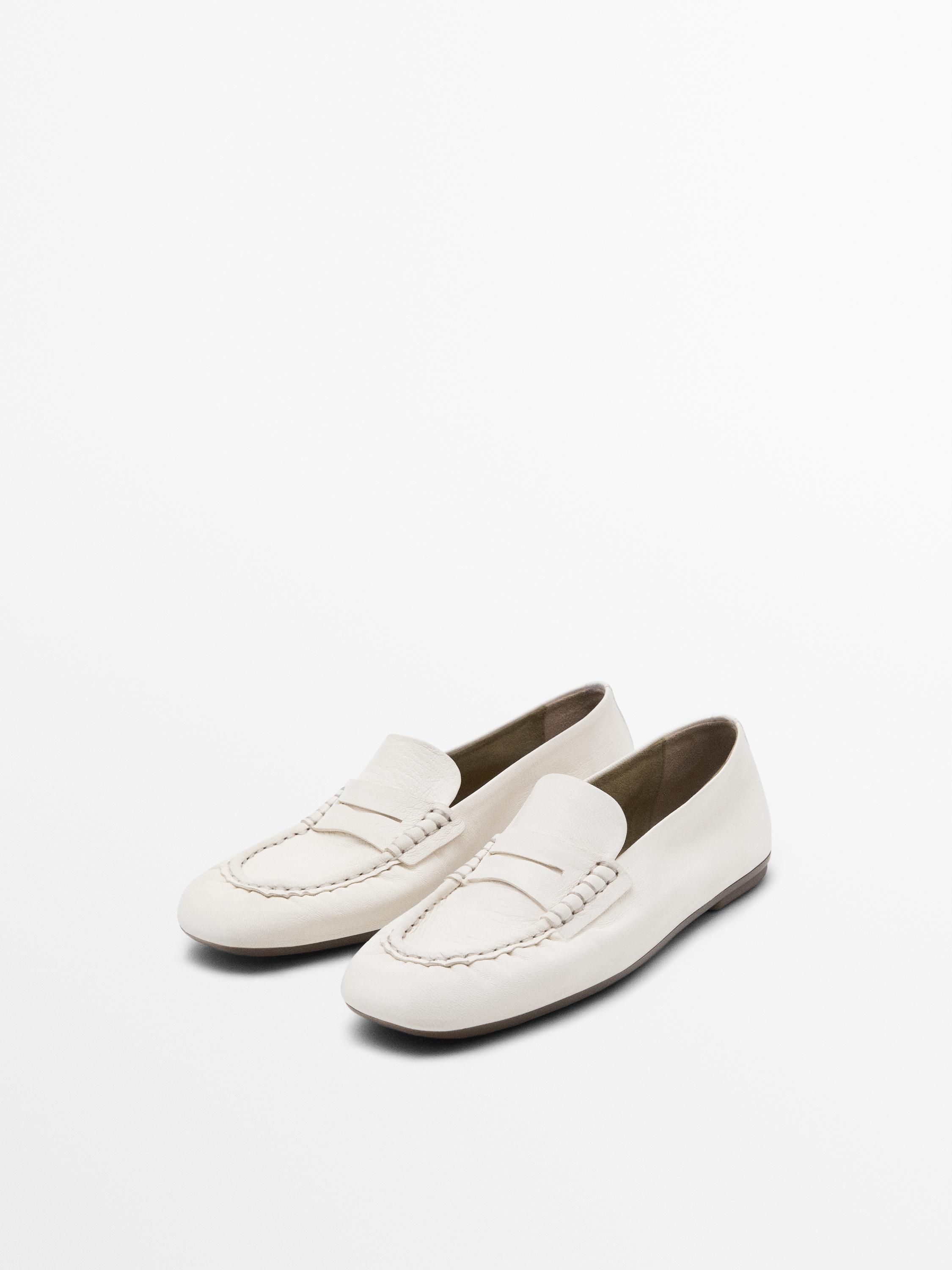 Side view of white loafers with braided detail on the instep and low sole.