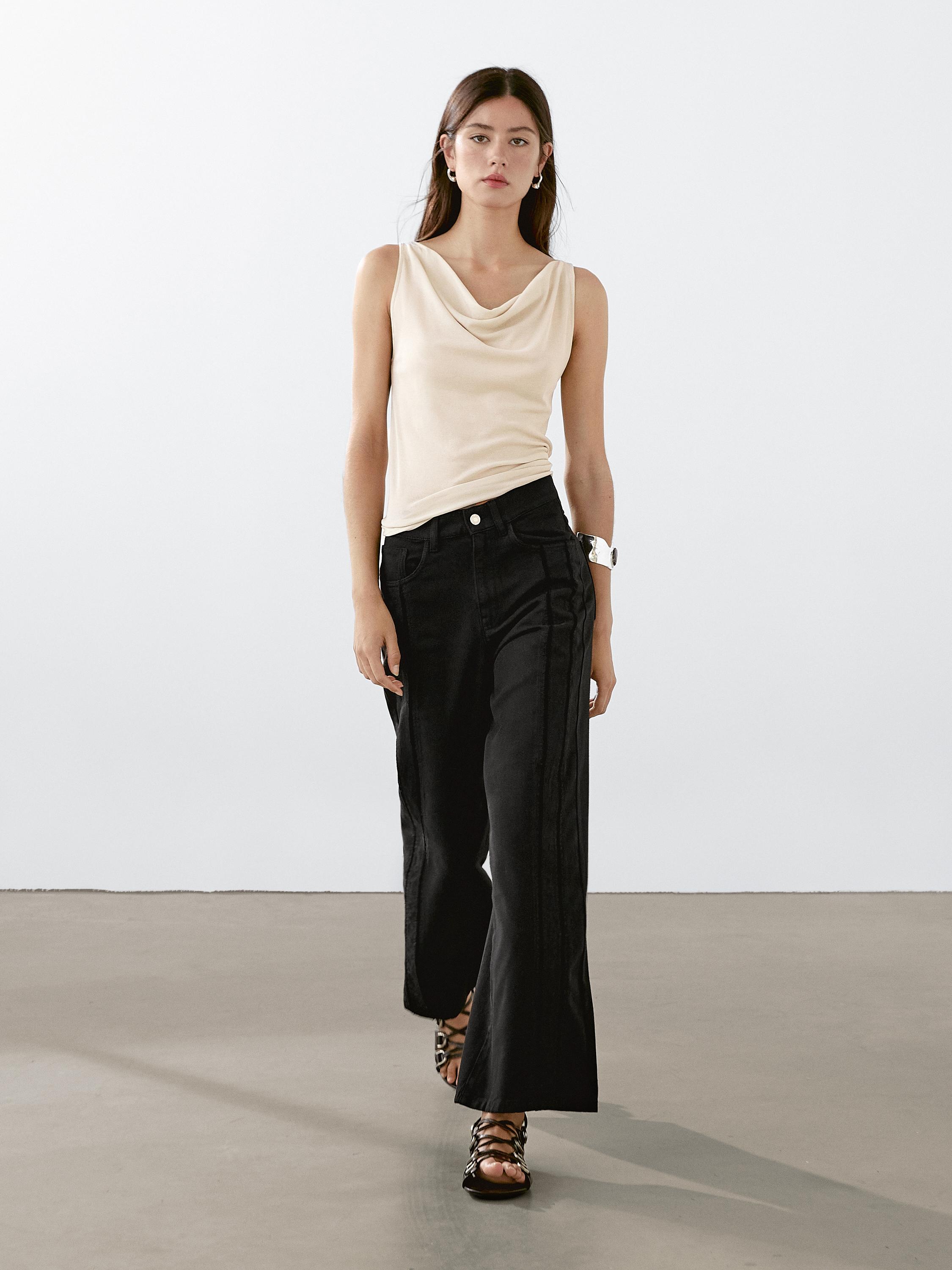 Ensemble composé d'un chemisier beige sans manches et d'un pantalon noir à jambes larges.