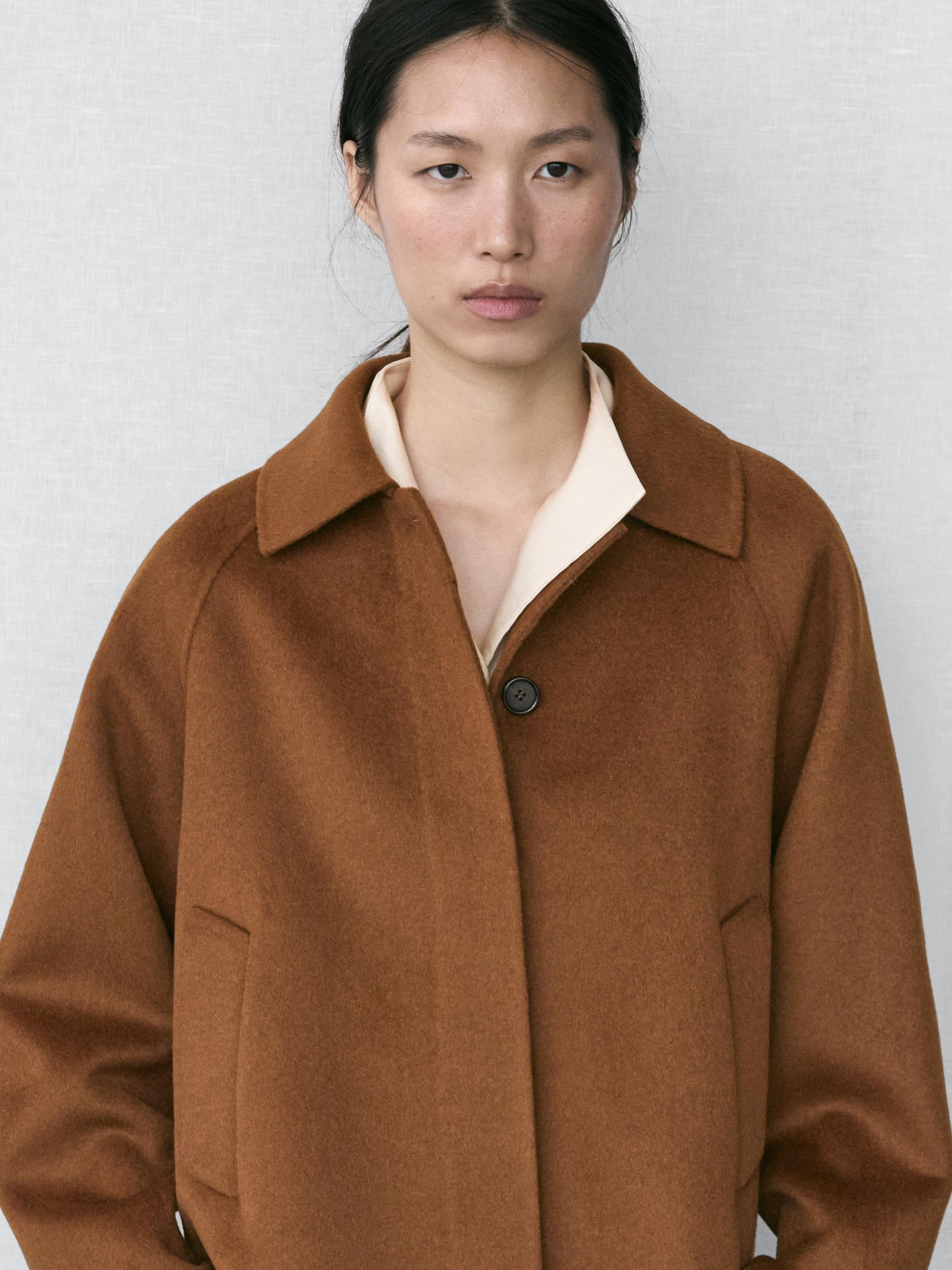 Mid-shot of a caramel coat with a classic collar, raglan sleeves, and side pockets.