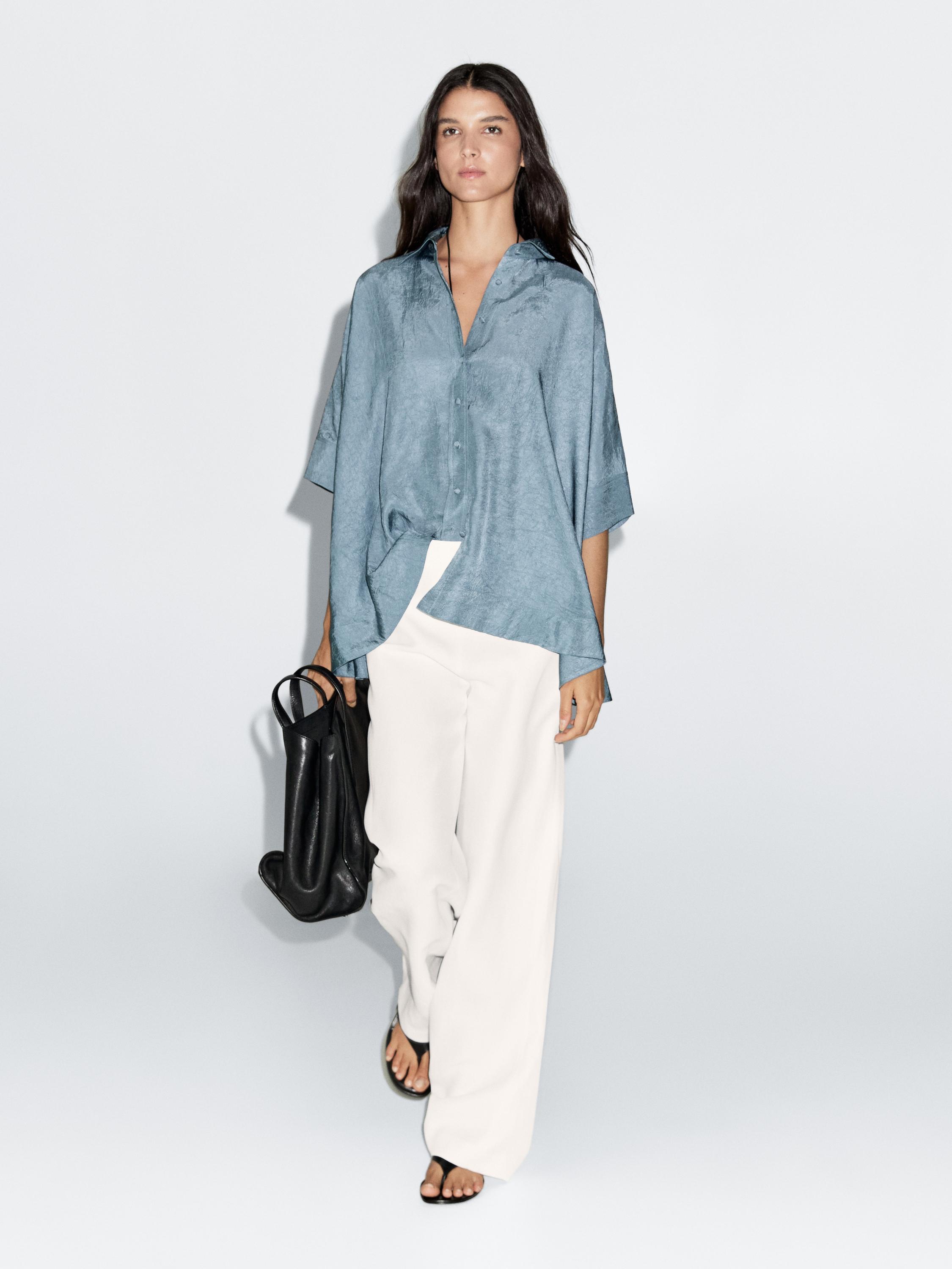 طقم بلوزة فضفاضة باللون الأزرق الفاتح مع أزرار مغطاة وبنطلون أبيض واسع.