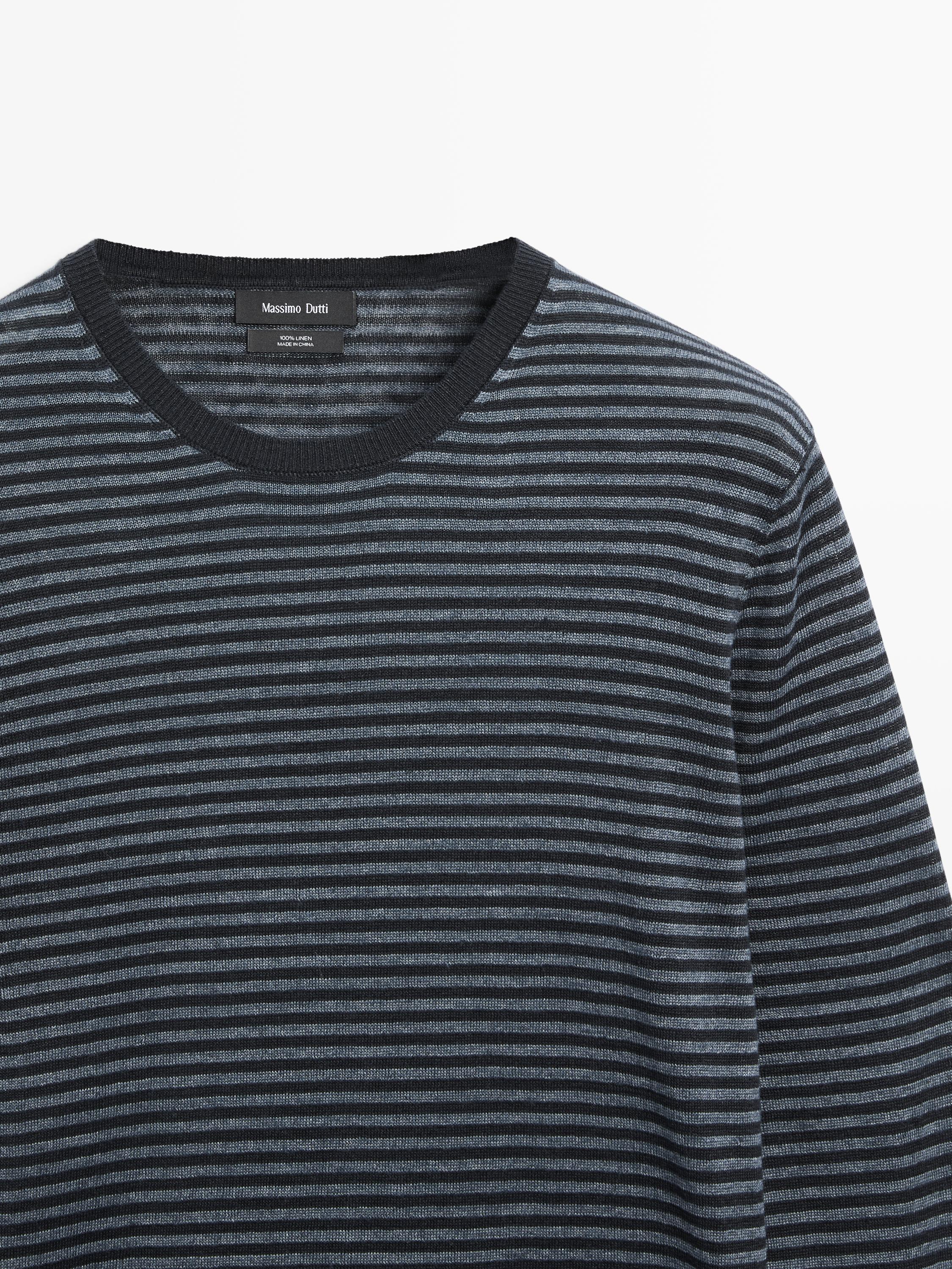 "Plano medio de suéter azul marino a rayas finas con cuello redondo y etiqueta visible en el interior del cuello."