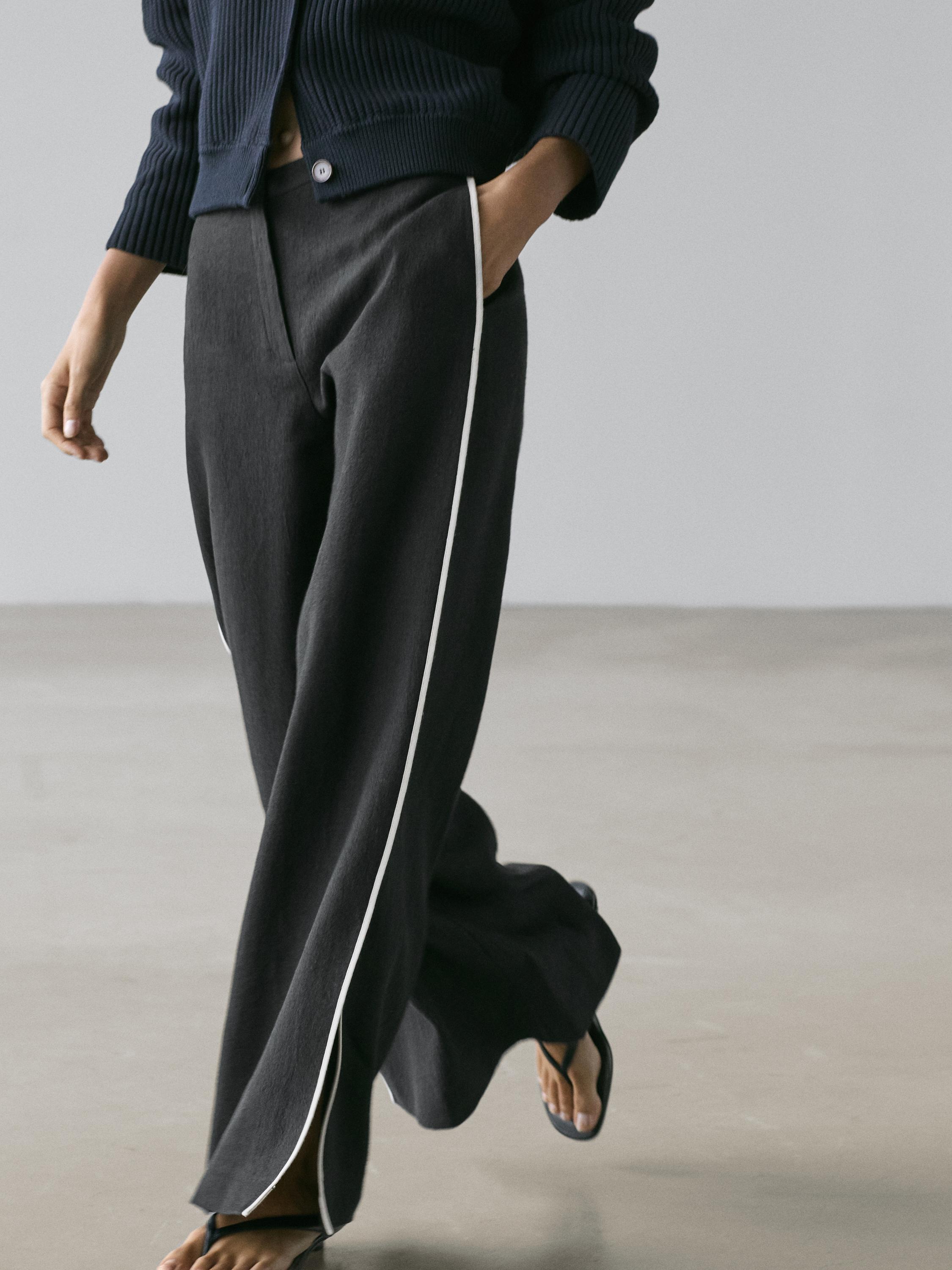 Halve opname van zwarte broek met wit contrast op zijnaden en zijzakken.