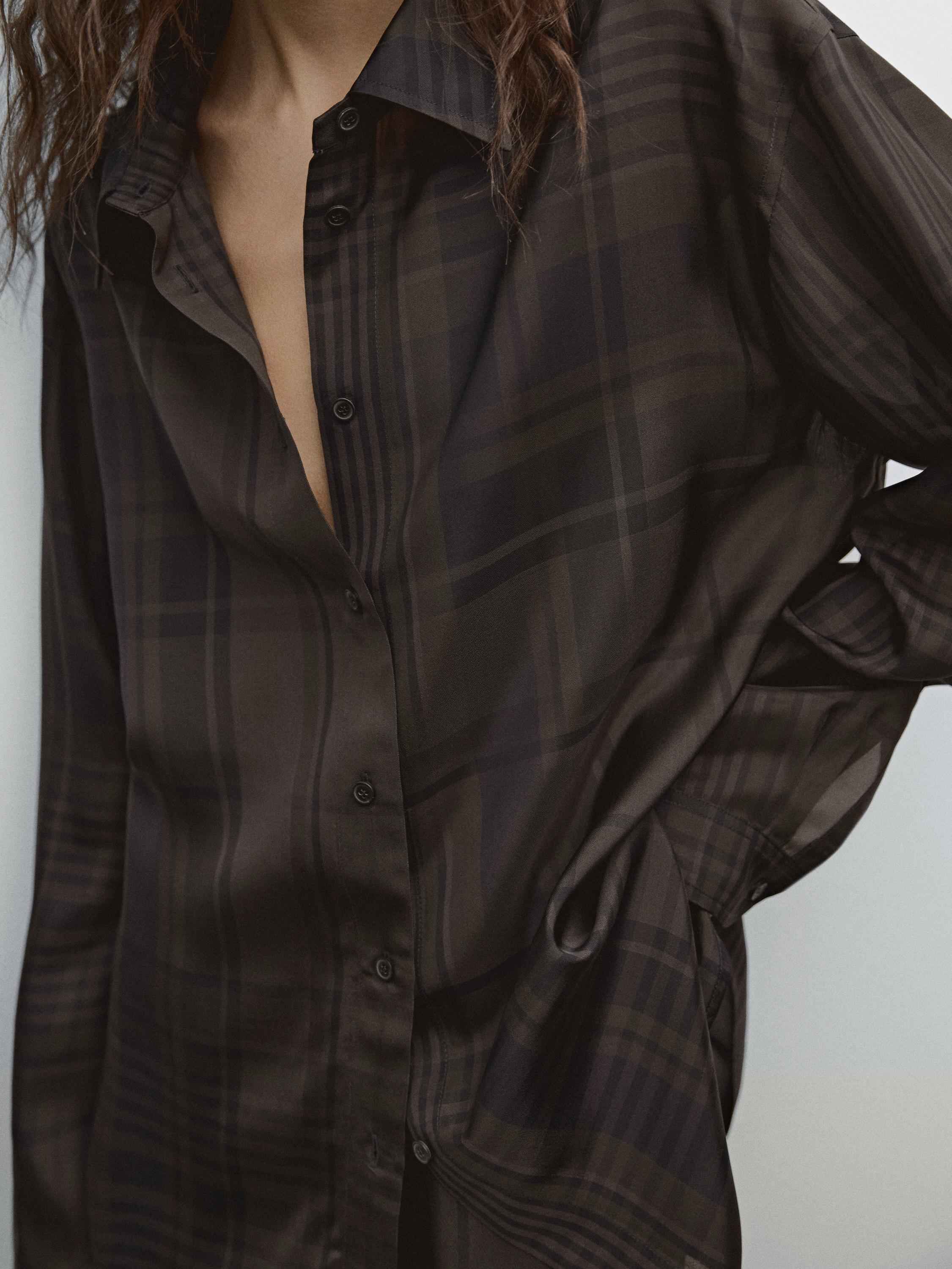 Detalle de camisa marrón con estampado a cuadros y botonadura frontal.