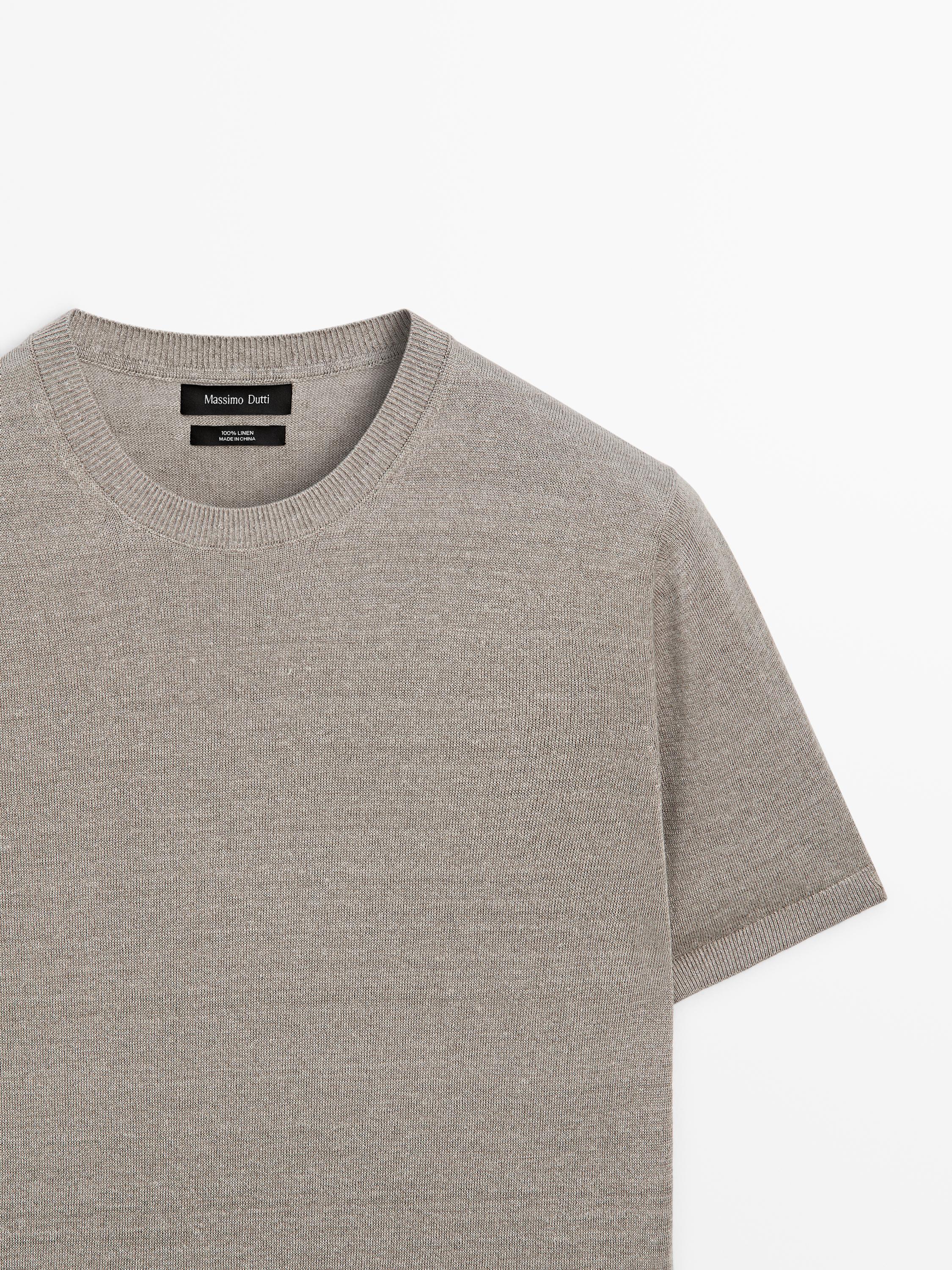 Pla mitjà de jersei gris amb coll rodó i mànigues curtes. Etiqueta visible amb text "Massimo Dutti".