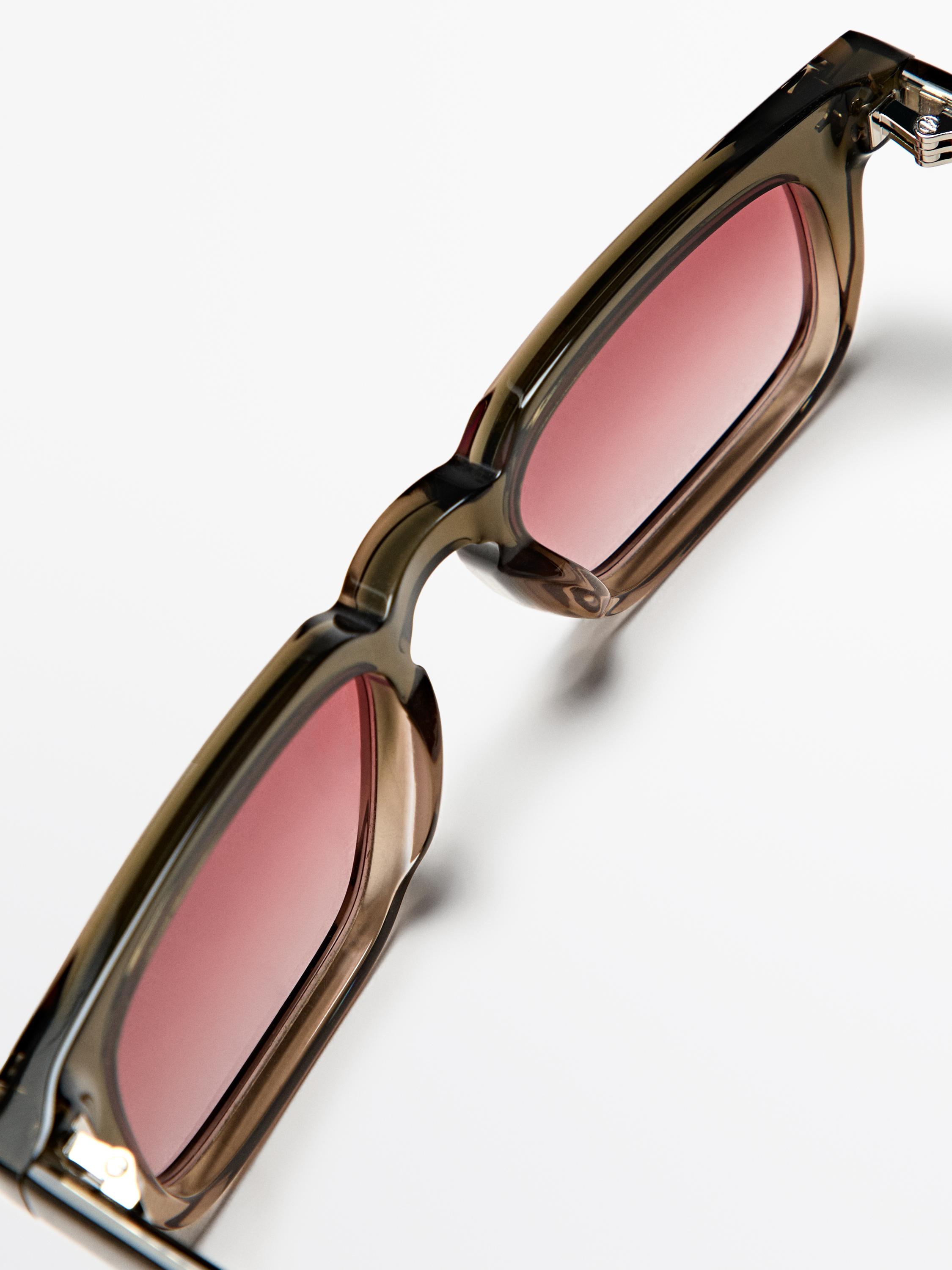 Toprak kahverengisi güneş gözlüklerinin pembe camlı ve kalın dikdörtgen çerçeveli detayı.