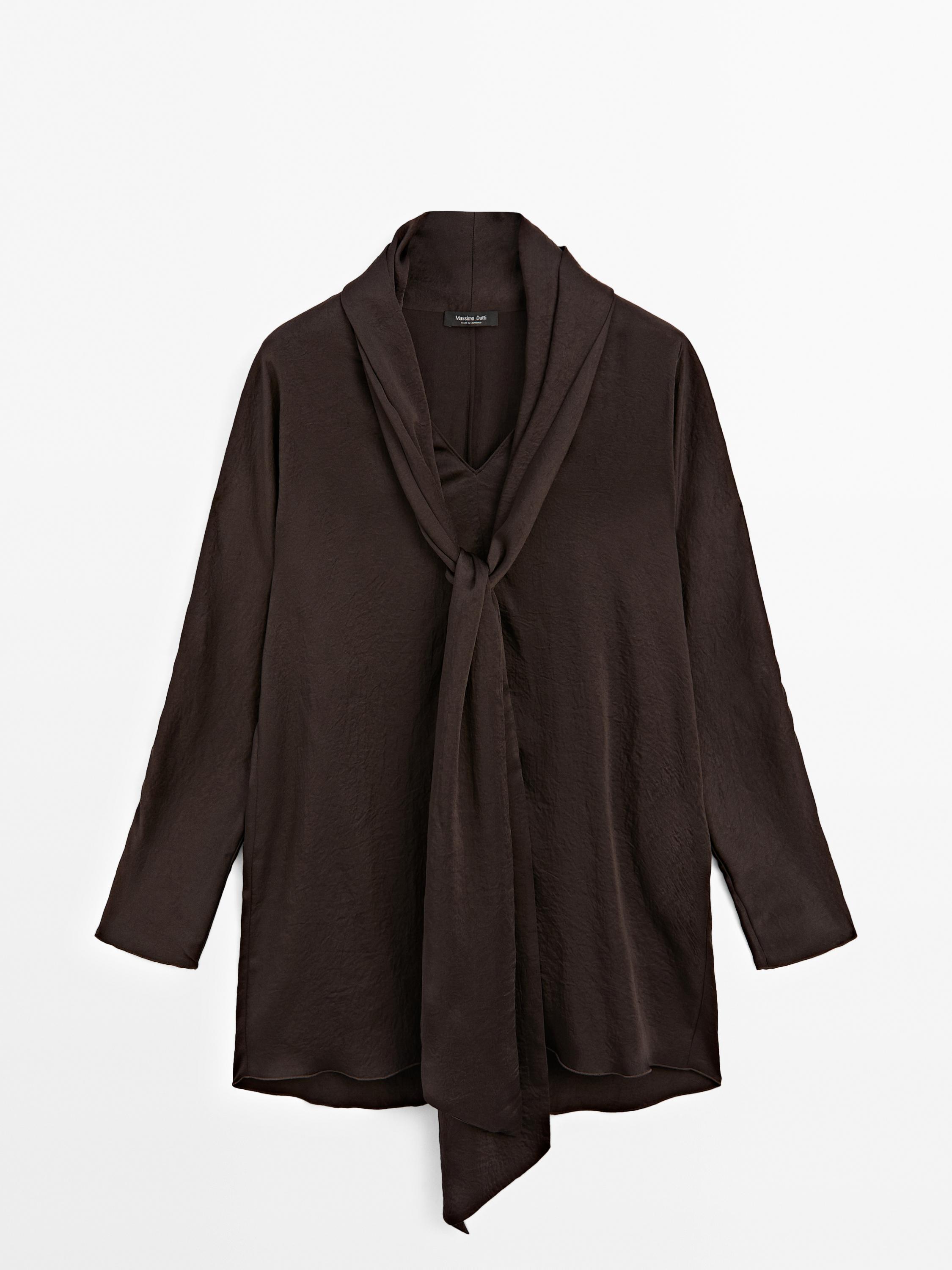 Sprednji pogled na ohlapno dolgo rjavo bluzo z ovratnikom s pentljo, dolgimi rokavi in asimetričnim robom.