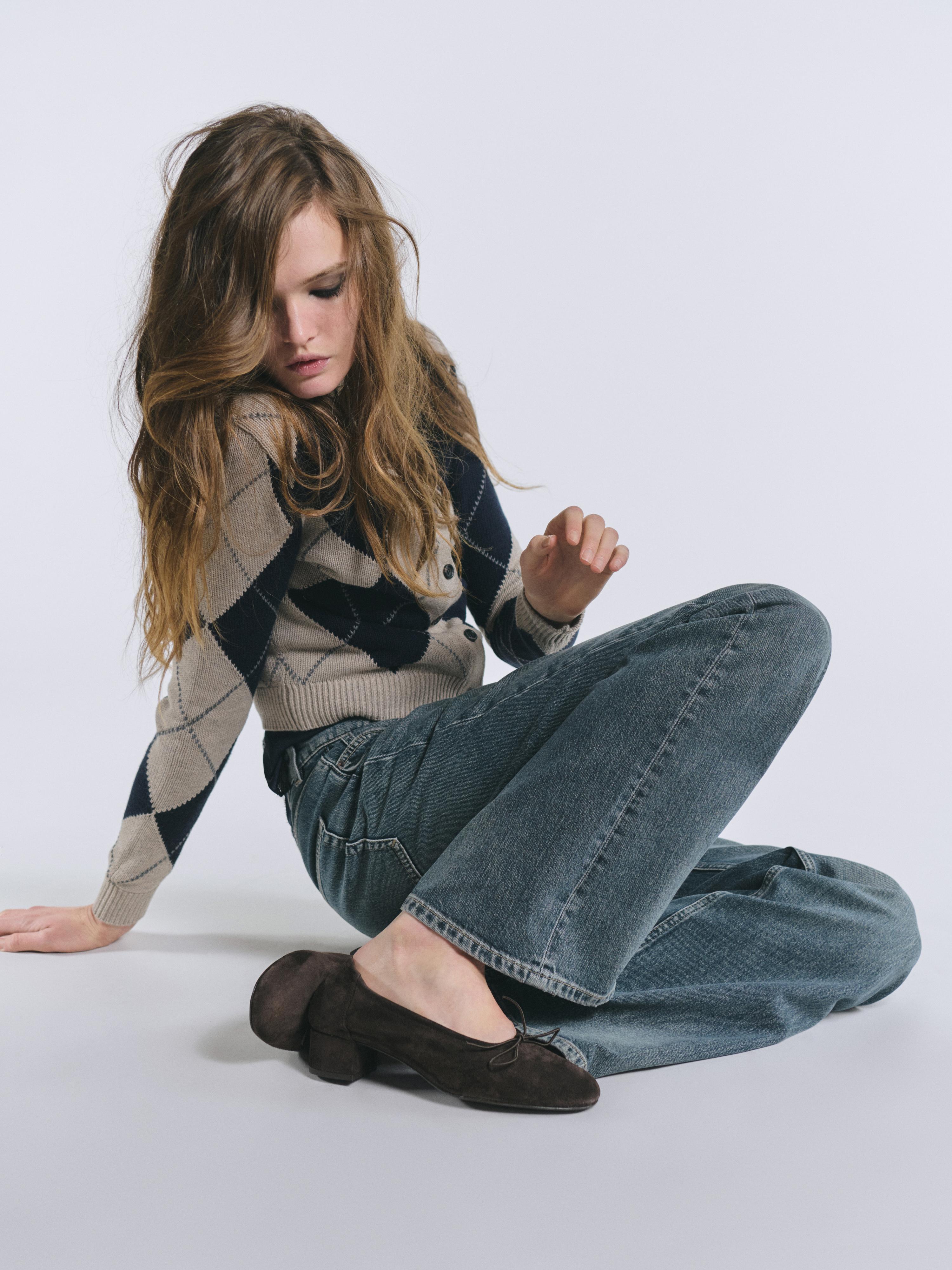 Navy blue argyle cardigan set with blue jeans.