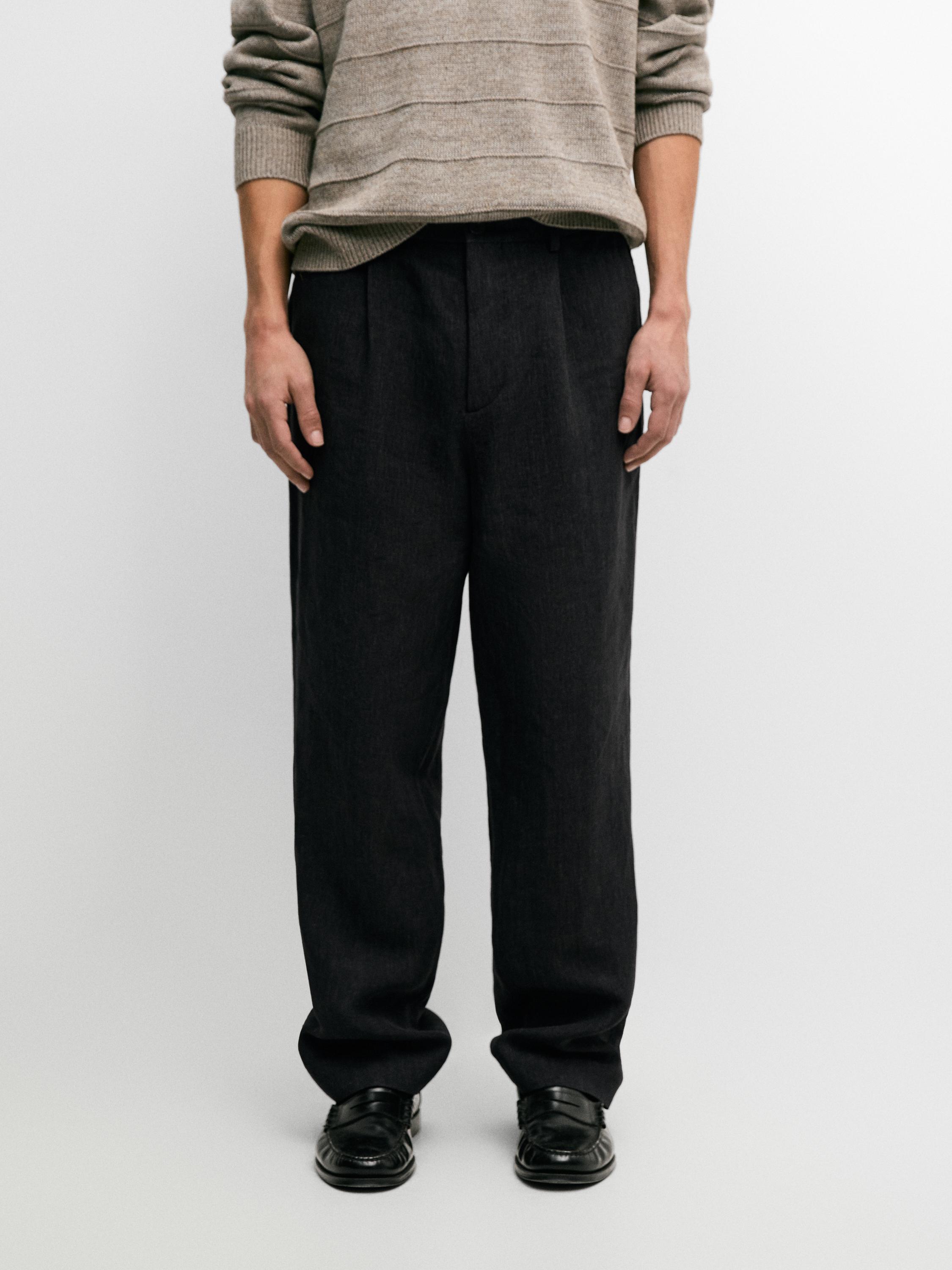 Zestaw składający się z granatowych spodni z zaszewkami i bocznymi kieszeniami, połączony z beżowym swetrem w poziome paski.