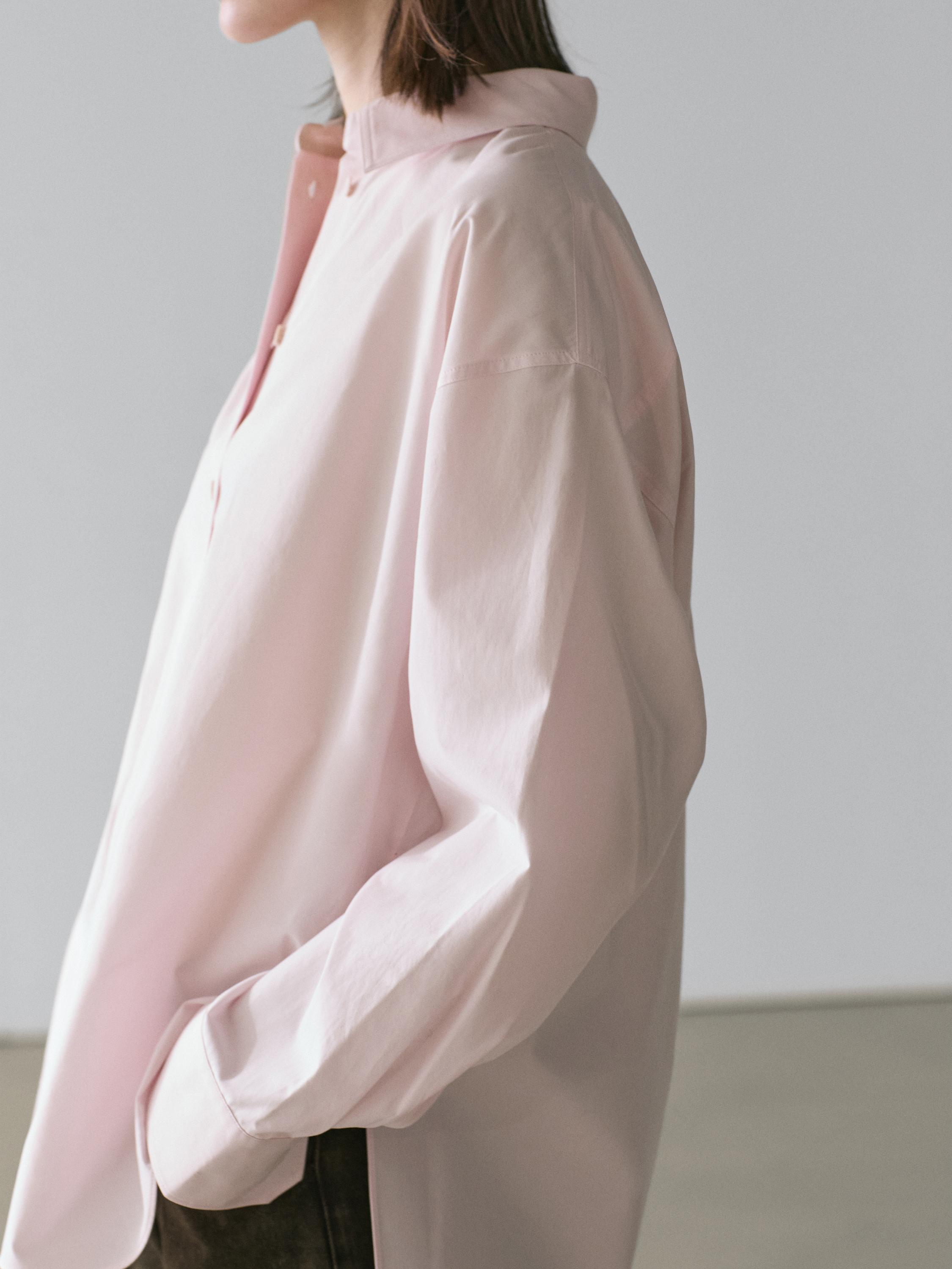 Kamiseta arrosa baten plano ertaina, lepo klasikoa eta mahuka luzeak dituena. Alboko poltsikoa ikusgai.