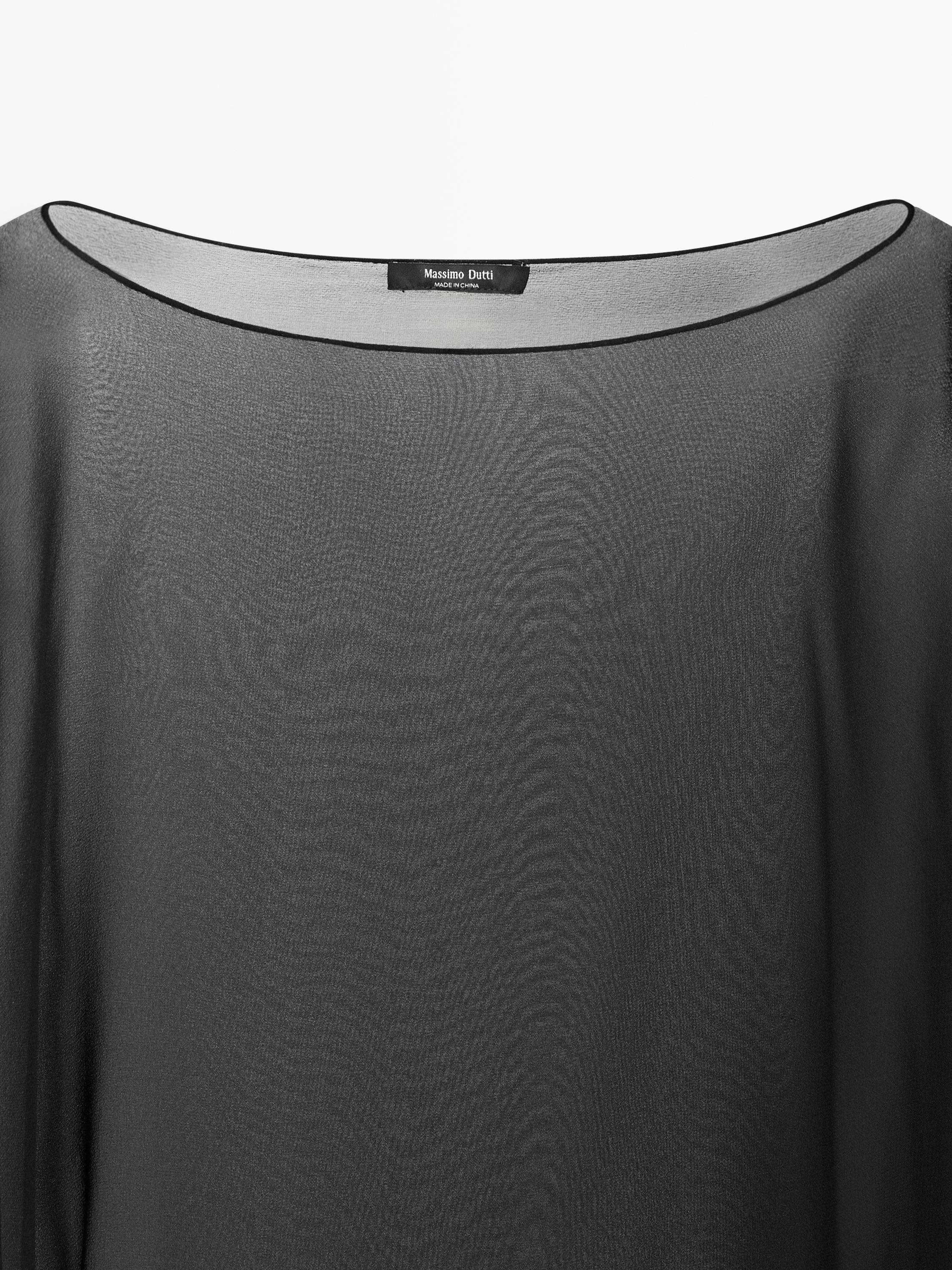 "Detale kołnierza czarnej bluzki z widoczną metką z napisem 'Massimo Dutti Made in China'."