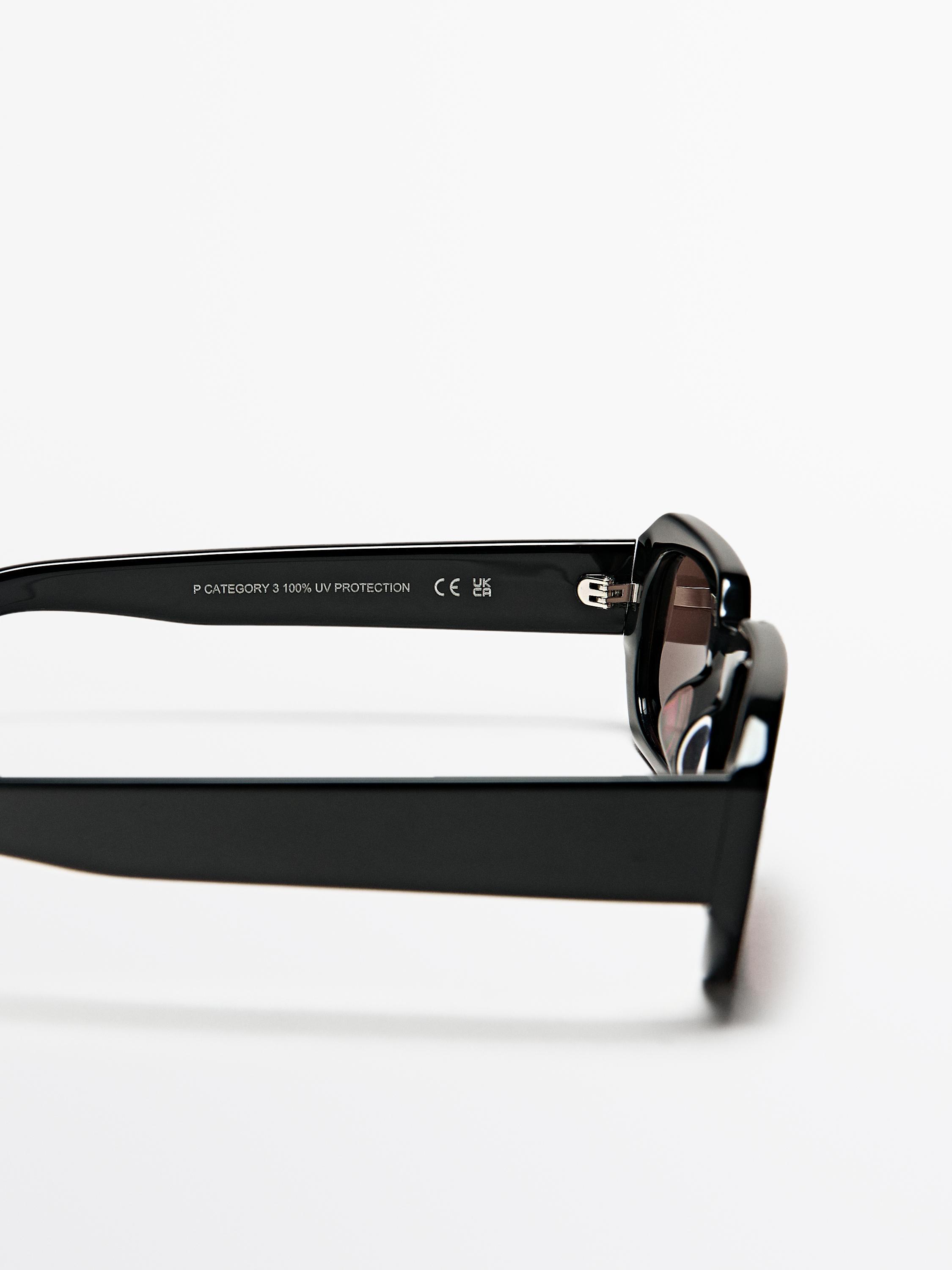 Eguzkitako betaurreko beltzen xehetasuna, "P CATEGORY 3 100% UV PROTECTION" testua duena, patillan.