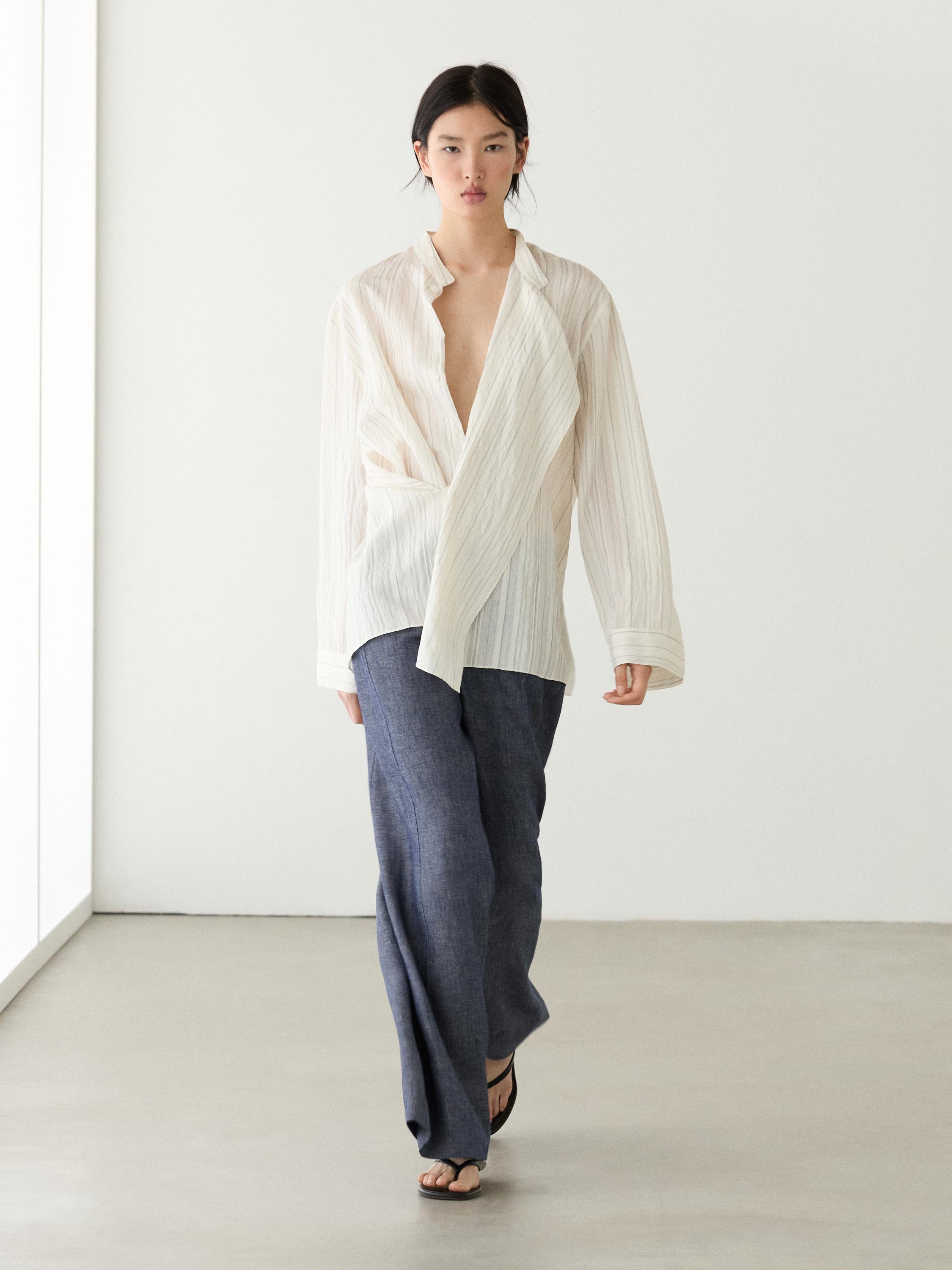 Long-sleeved white wrap blouse and high-waisted dark blue palazzo pants set.