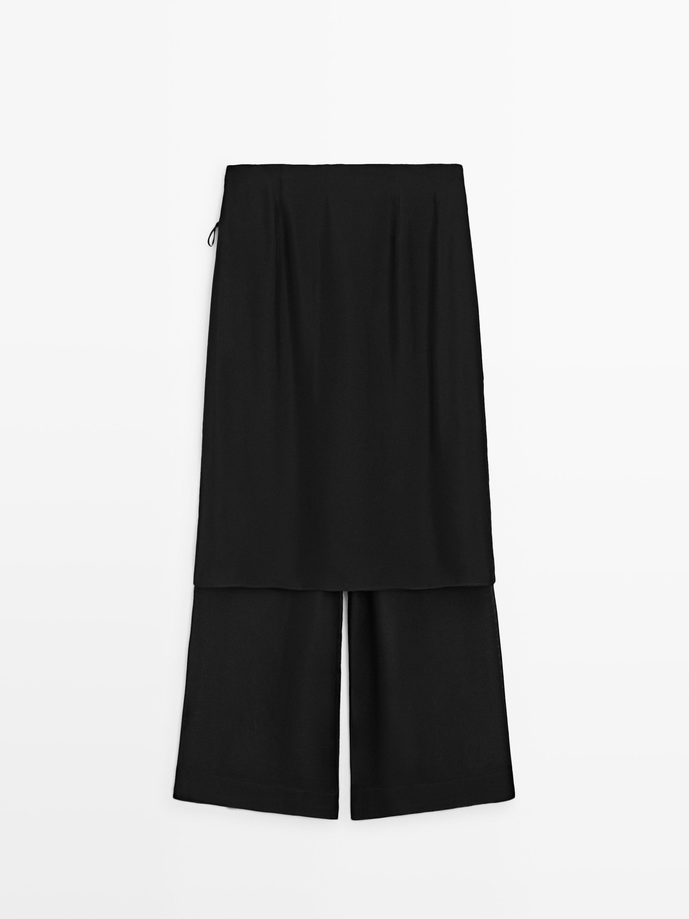 Μπροστινή όψη μαύρου παντελονιού με σχέδιο φούστας από πάνω, ίσια γραμμή και μήκος μέχρι τον αστράγαλο.