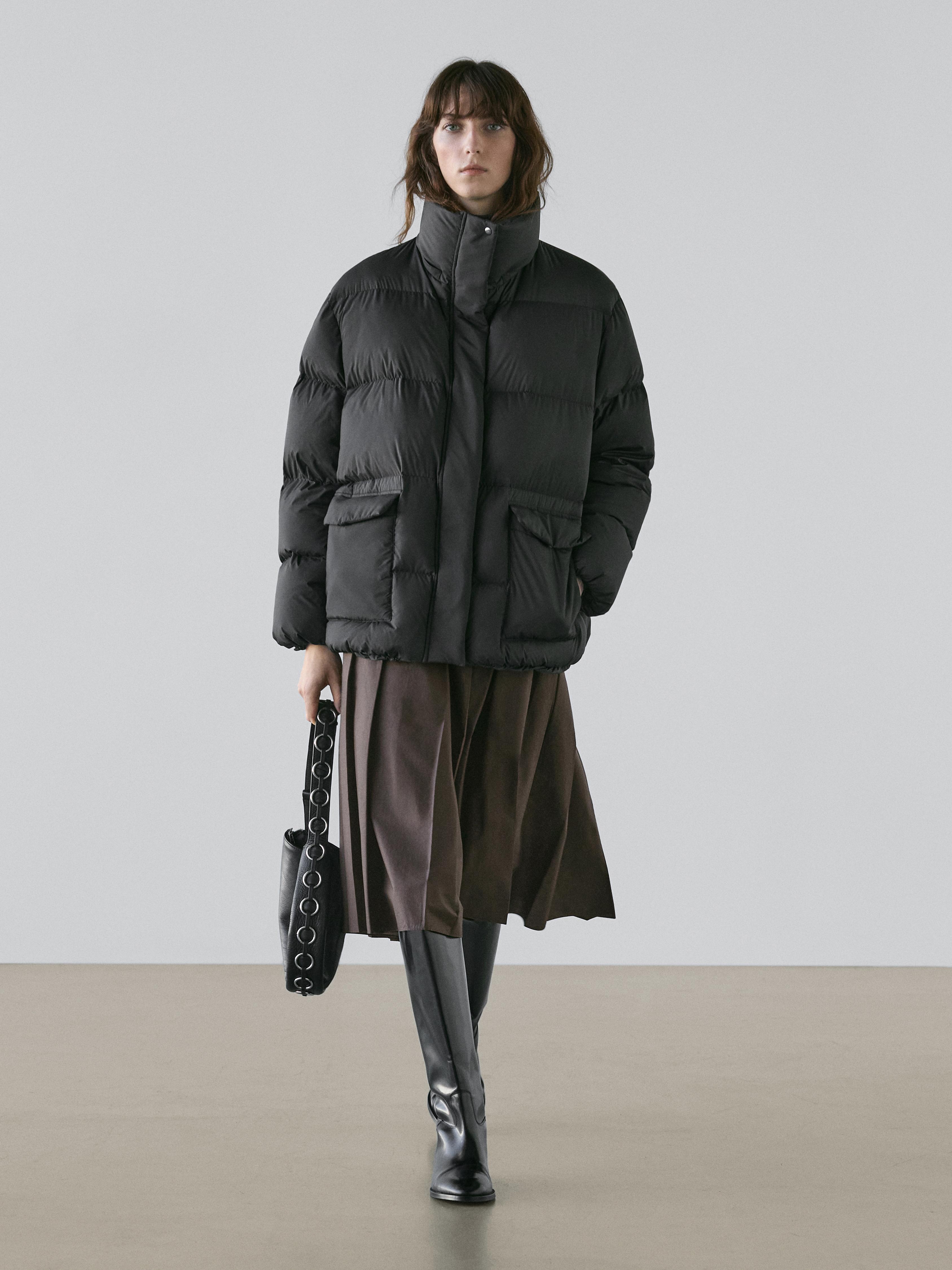 Must mustitud tepitud jope esitaskutega, pruun seelik ja mustad kõrged saapad.