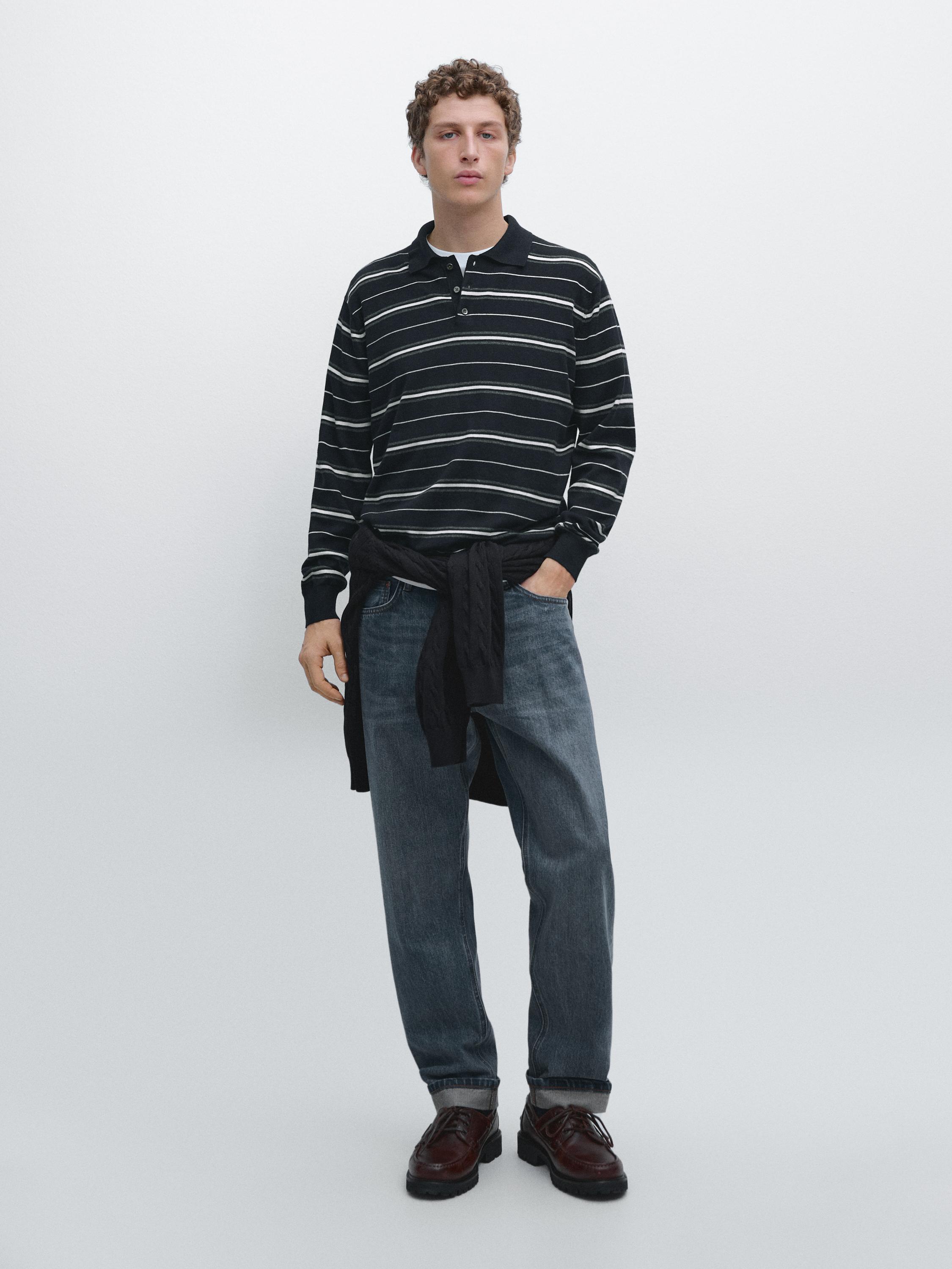 Conjunto de jersey azul marino a rayas con cuello alto, pantalones vaqueros y zapatos marrones.