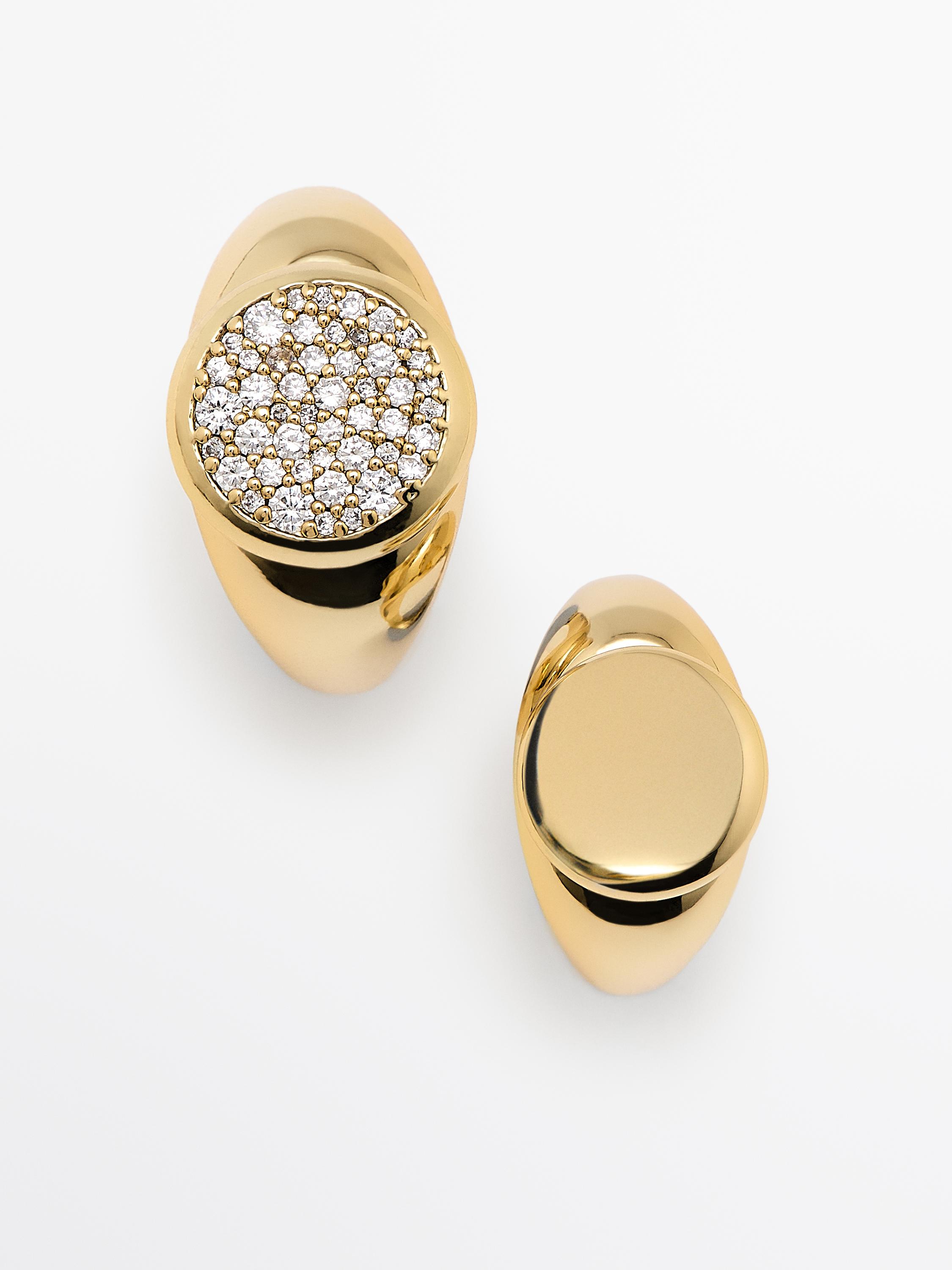 Vue de dessus de deux anneaux dorés, l'un incrusté de brillants sur le dessus et l'autre avec une surface lisse.