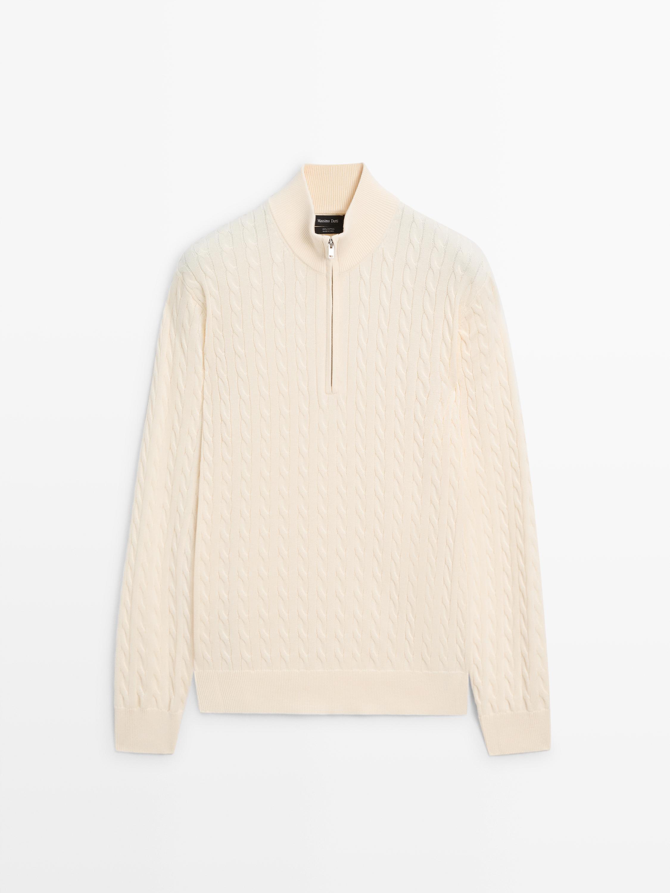 منظر أمامي لـ "jersey" بلون بيج فاتح وياقة وهمية وسحاب، وتصميم محبوك بضفائر وأكمام طويلة.