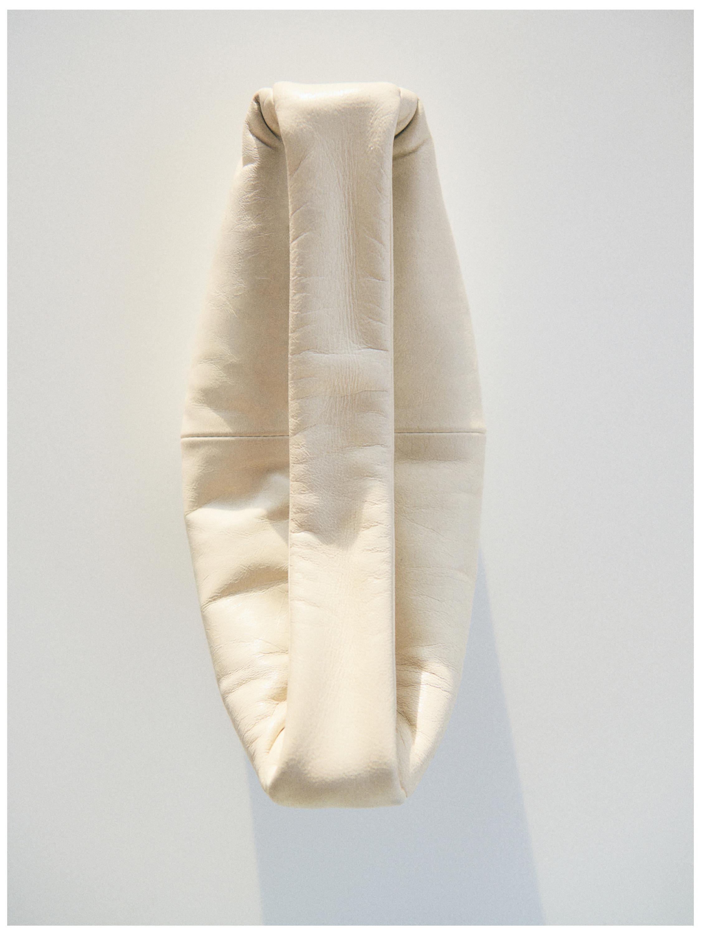 "Πλάγια όψη λευκής τσάντας με δομημένο σχέδιο και φαρδιά λαβή."