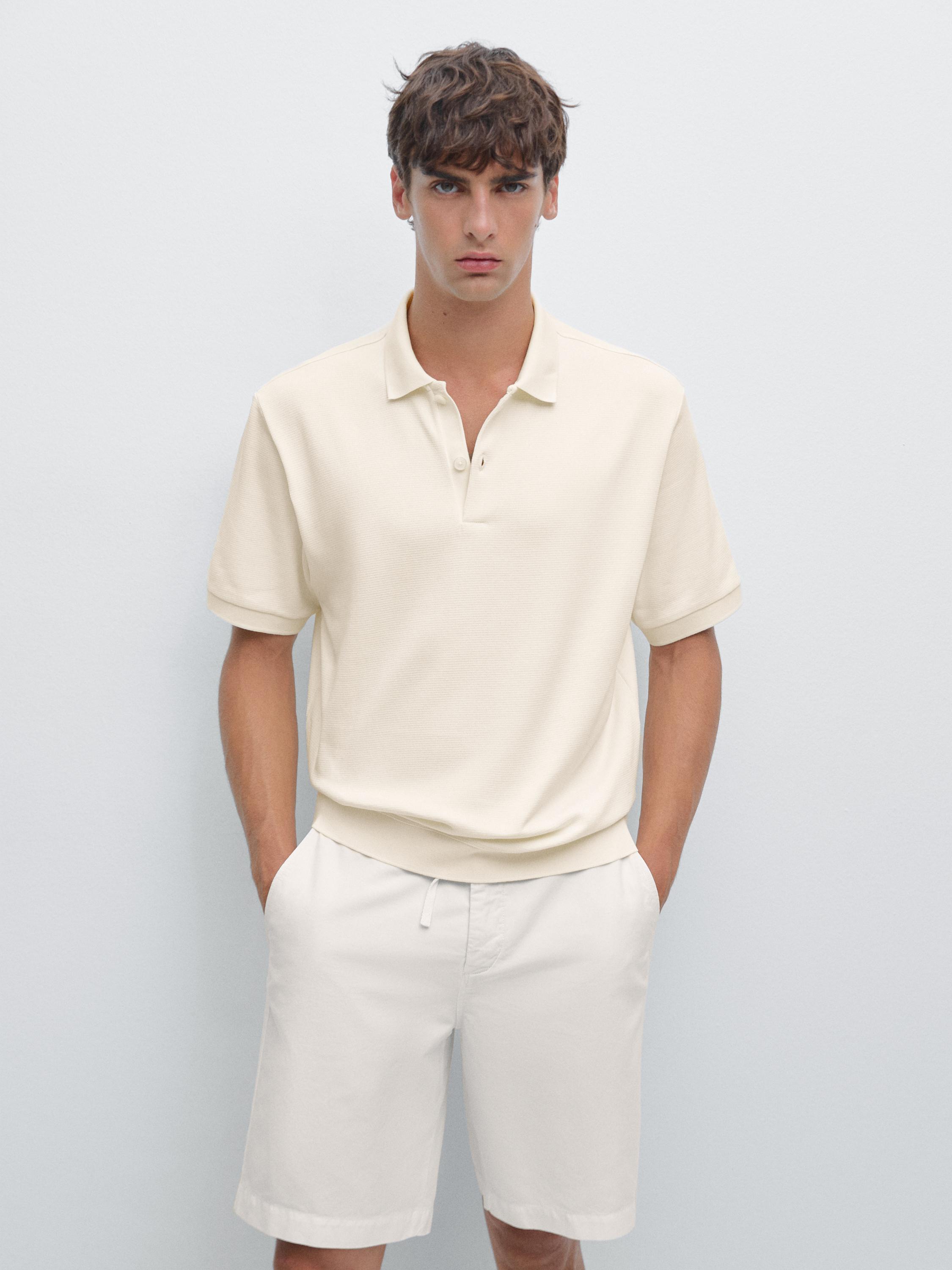 Ensemble de polo beige à manches courtes à col boutonné et short blanc avec poches latérales.
