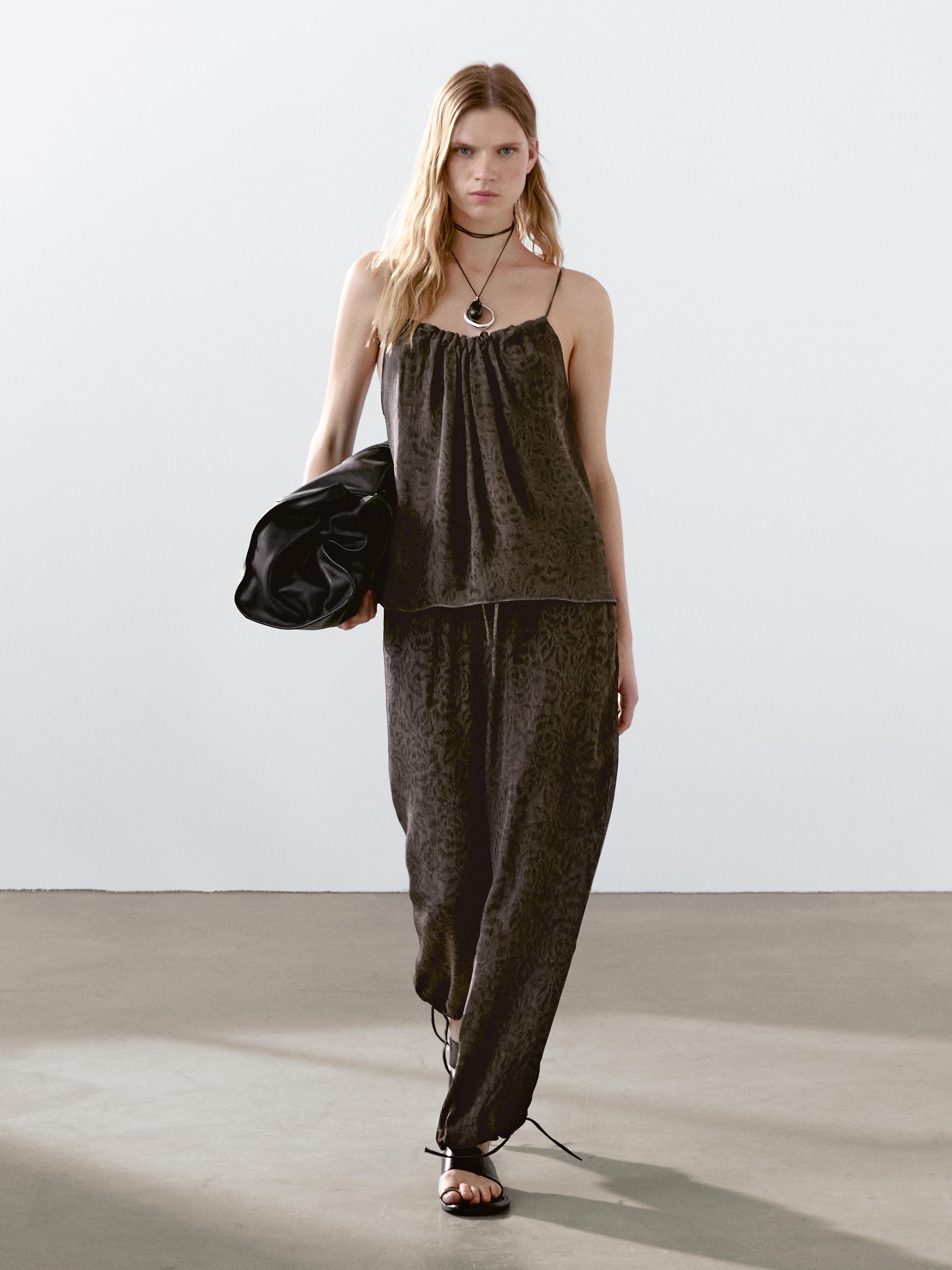 طقم مكون من توب بحمالات وبنطلون طويل أسود بنقشة خفيفة.