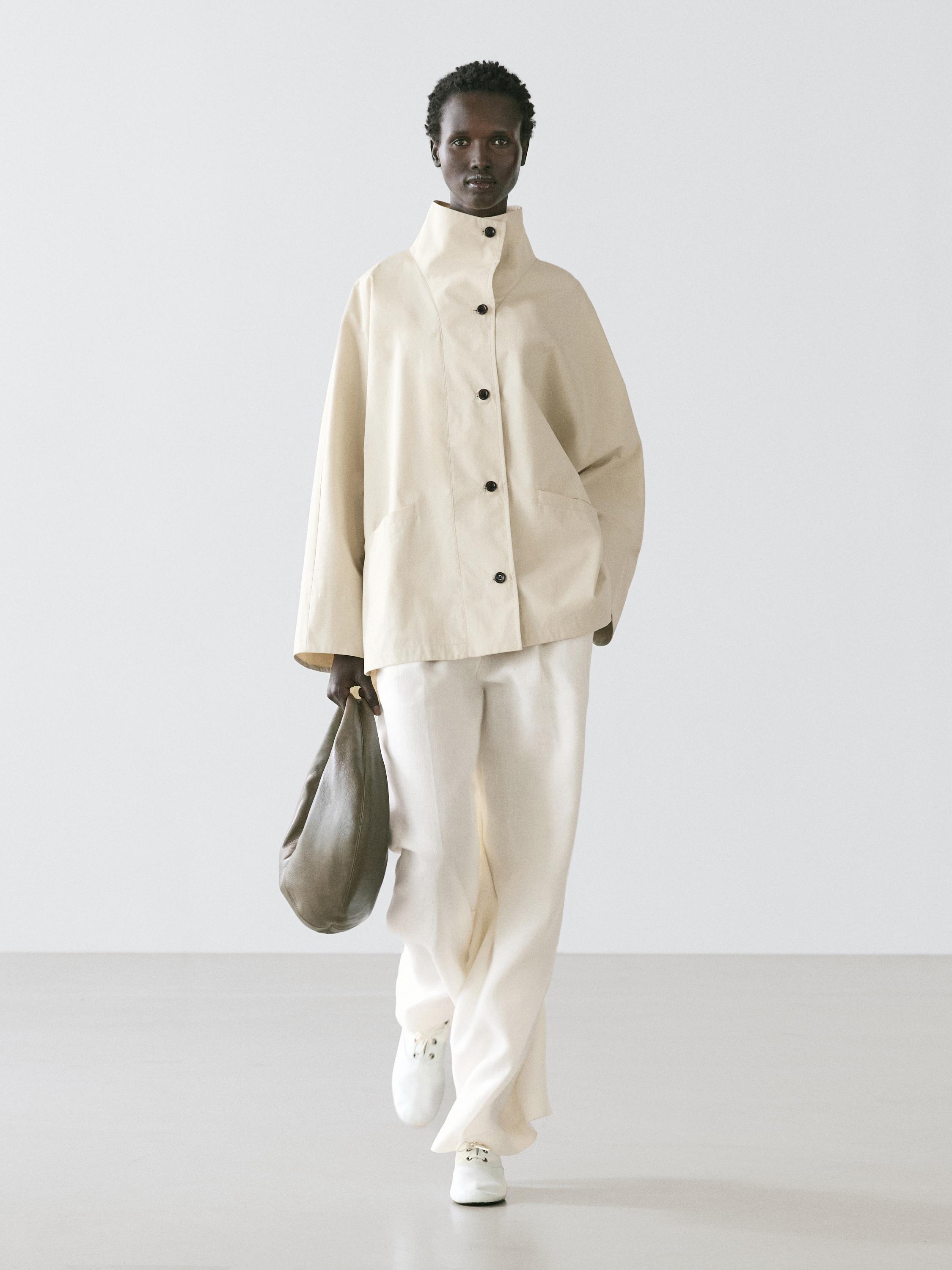 Raw jacket set with a stand-up collar and black buttons, raw wide-leg pants, and white sneakers.