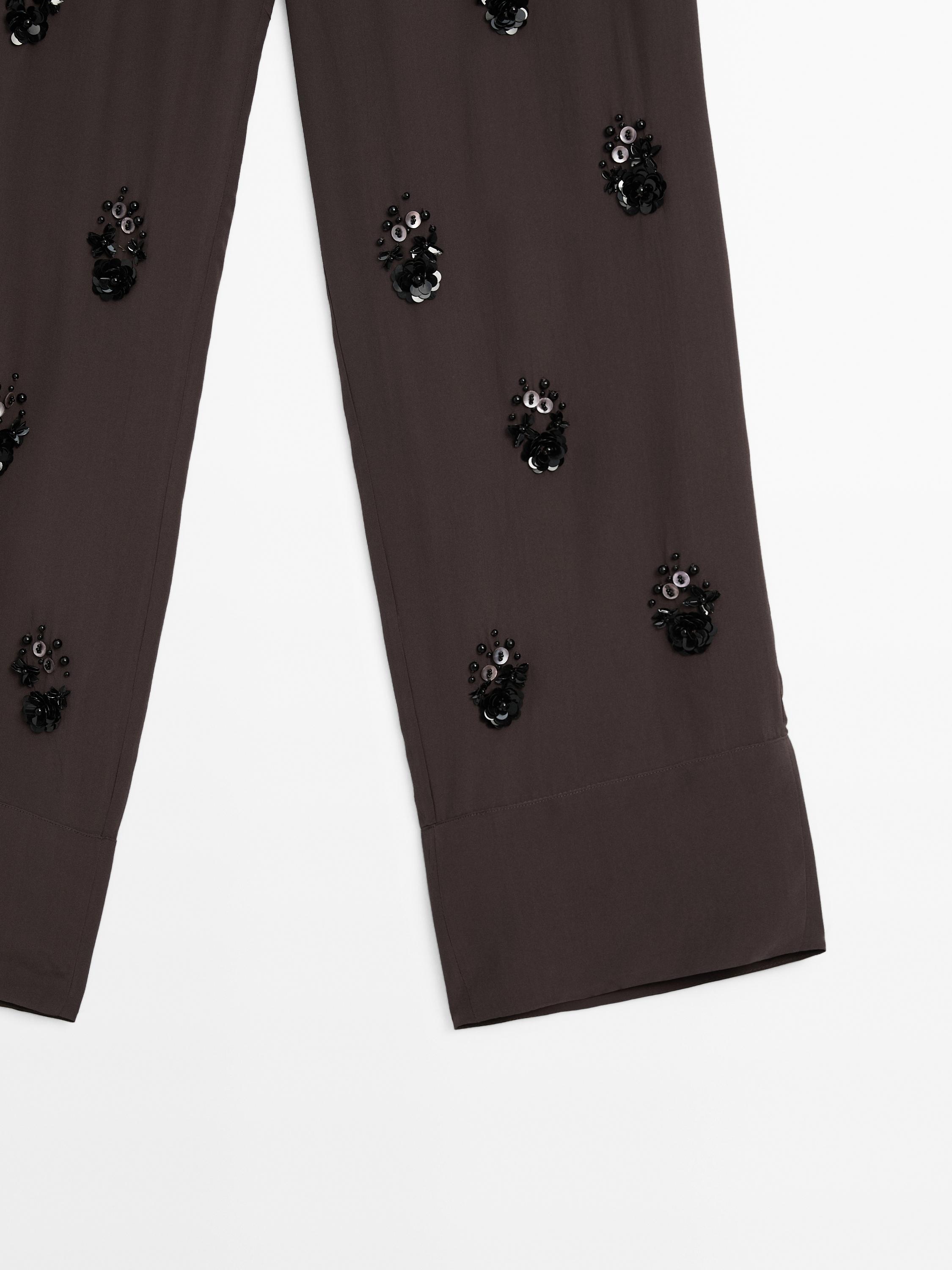 Flowing trousers with floral appliqués