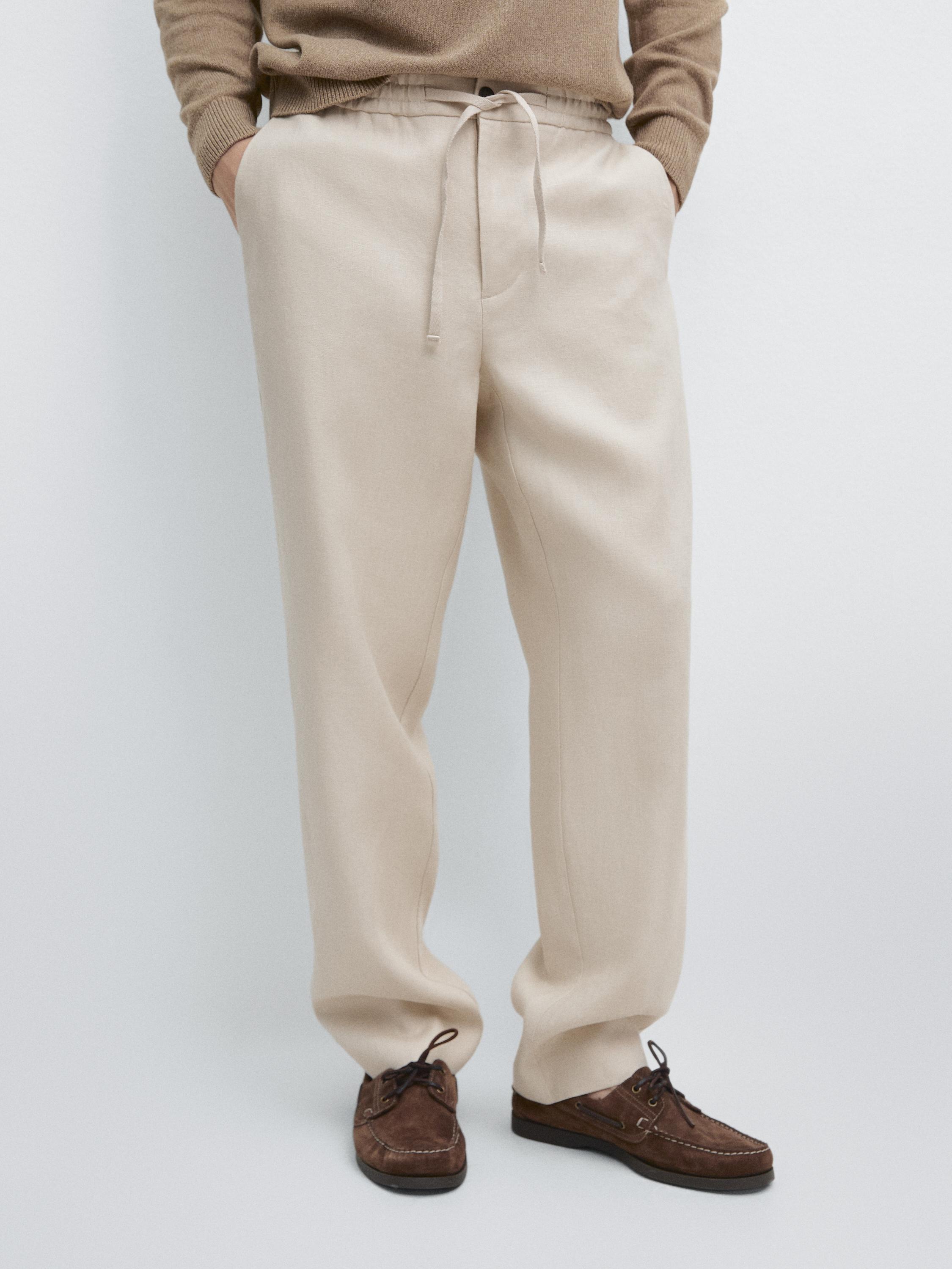 Ensemble de pantalon beige avec taille élastique et cordon ajustable, poches latérales, coupe droite.