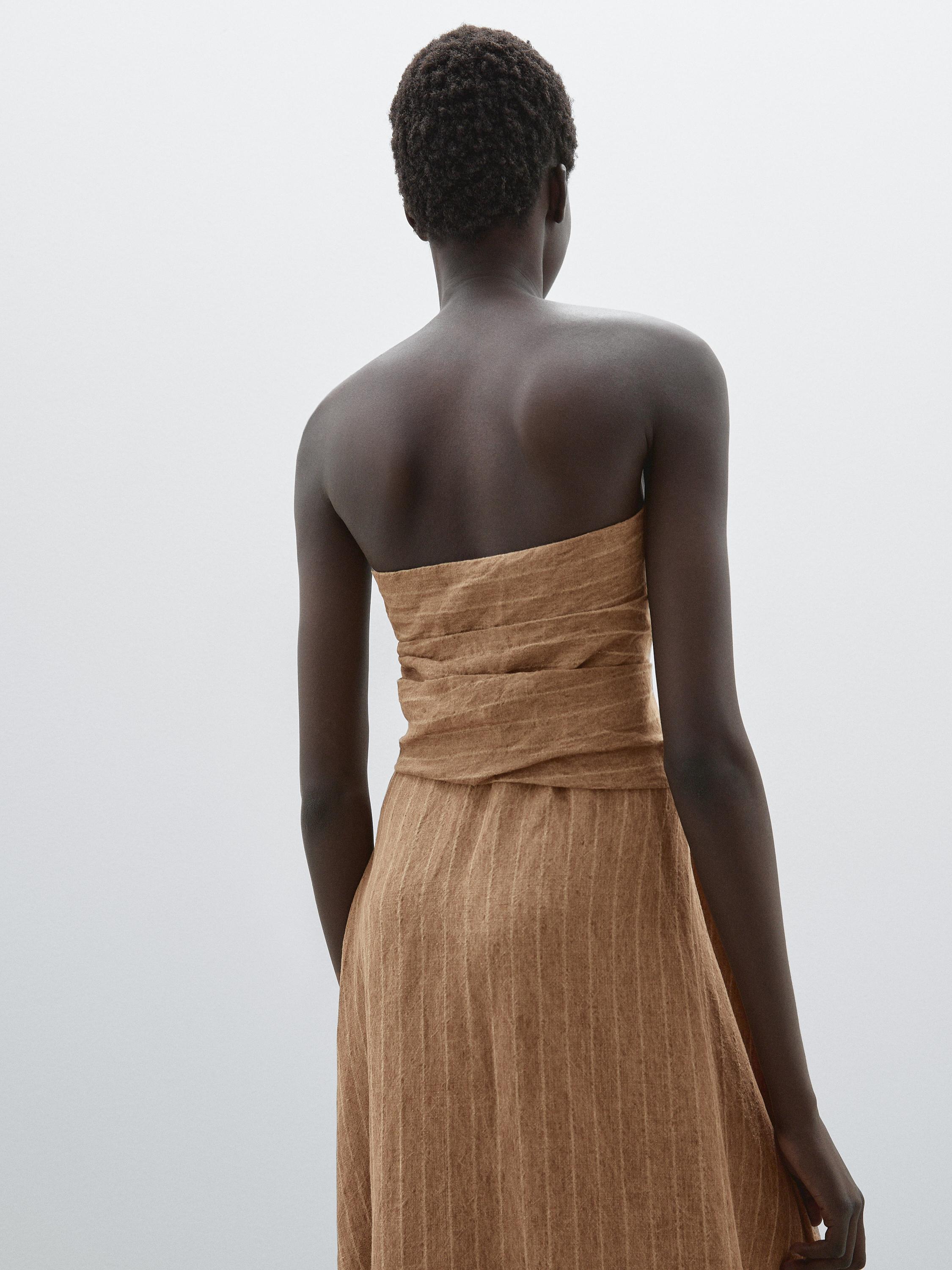 منظر خلفي لفستان بني بدون حمالات بنقشة مخططة.