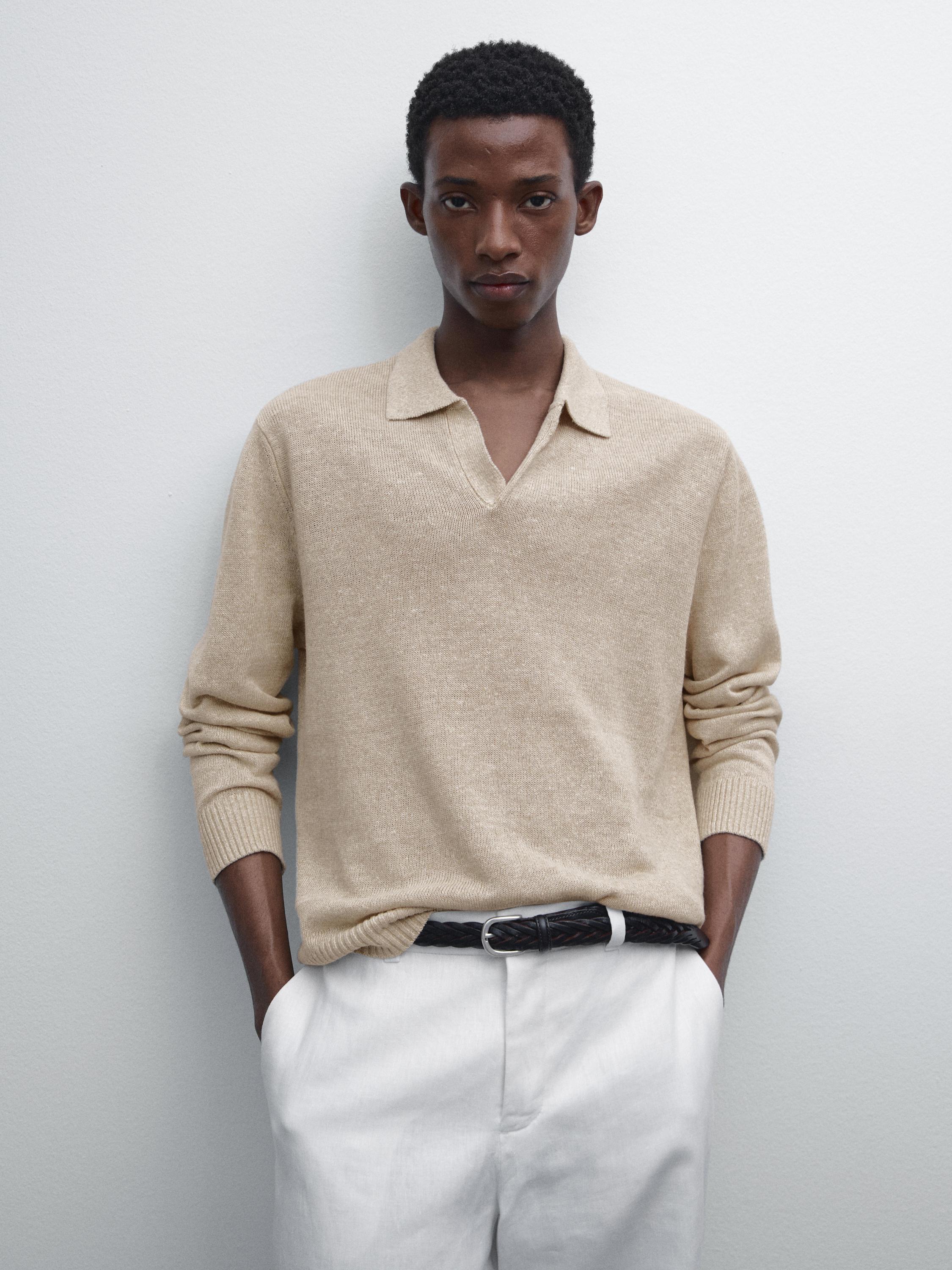 Ensemble pull beige à col et pantalon blanc, ceinture noire visible.