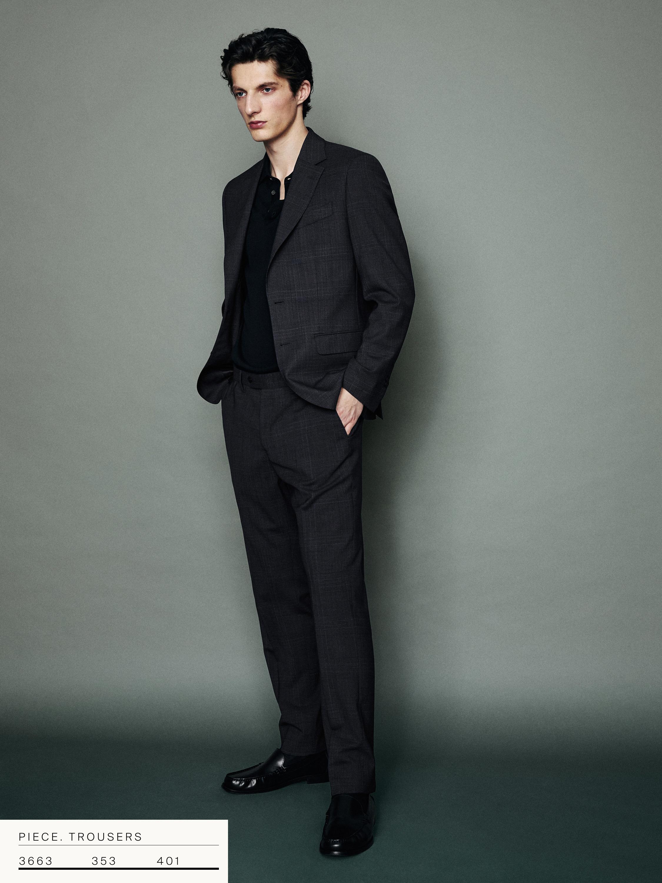 Traje ilun multzoa, bi botoiko jakarekin, alkandora beltzarekin eta praka berdinekin. Alboko poltsikoak ikusgai.