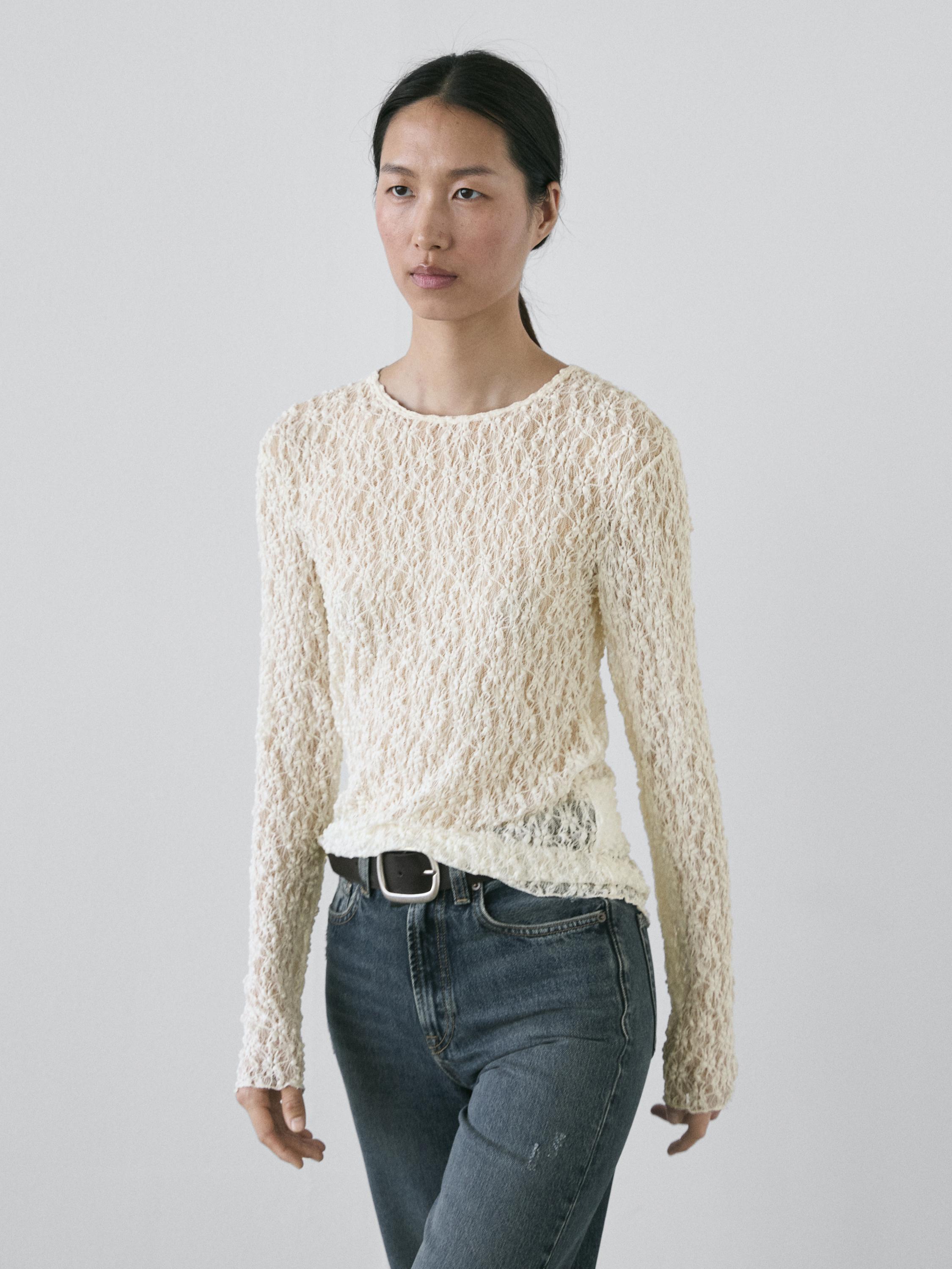 Ecru long-sleeved top set with openwork design and blue jeans.
