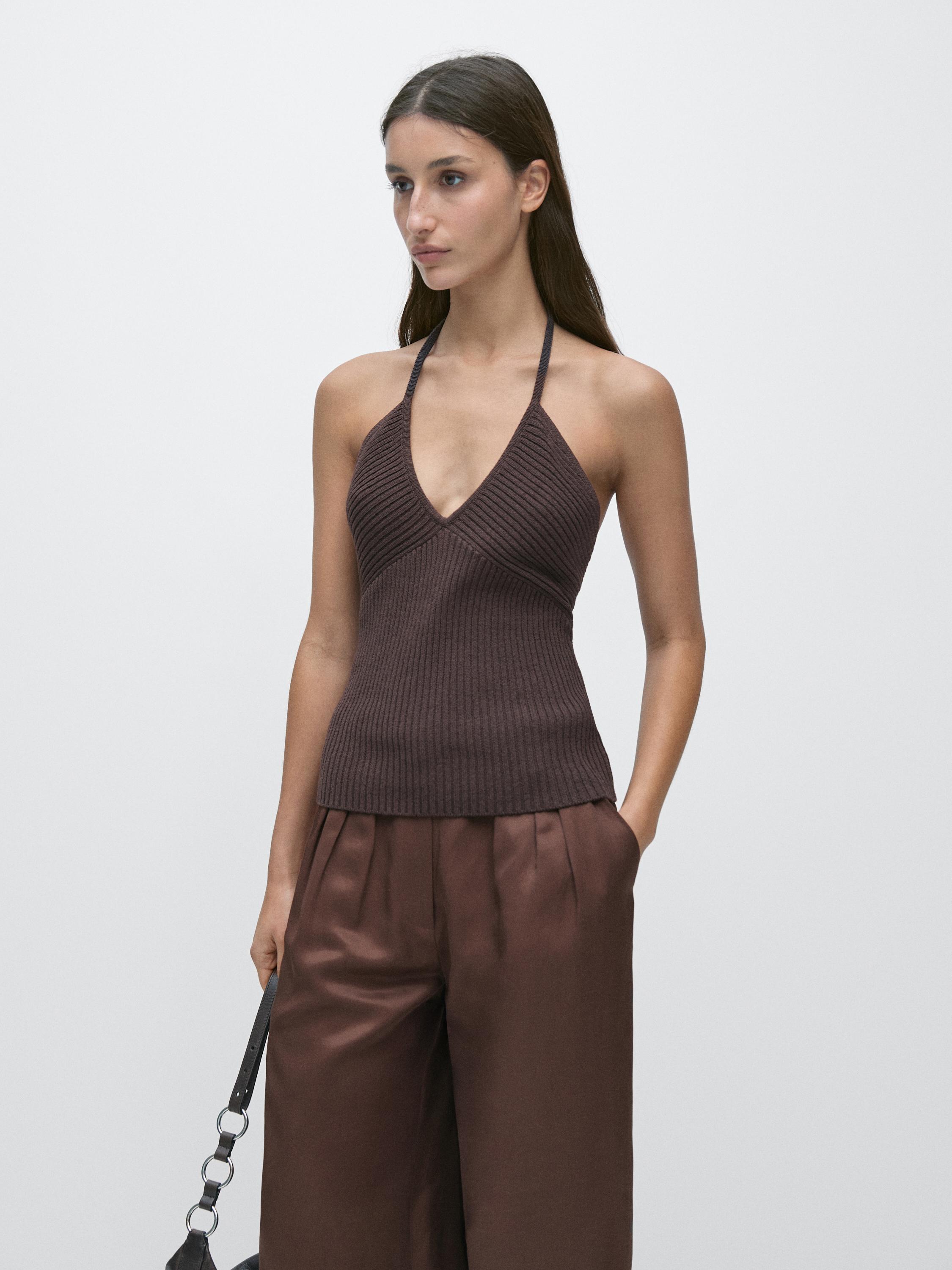 Conjunto de top berenjena con escote halter y pantalones marrones de talle alto con pliegues.
