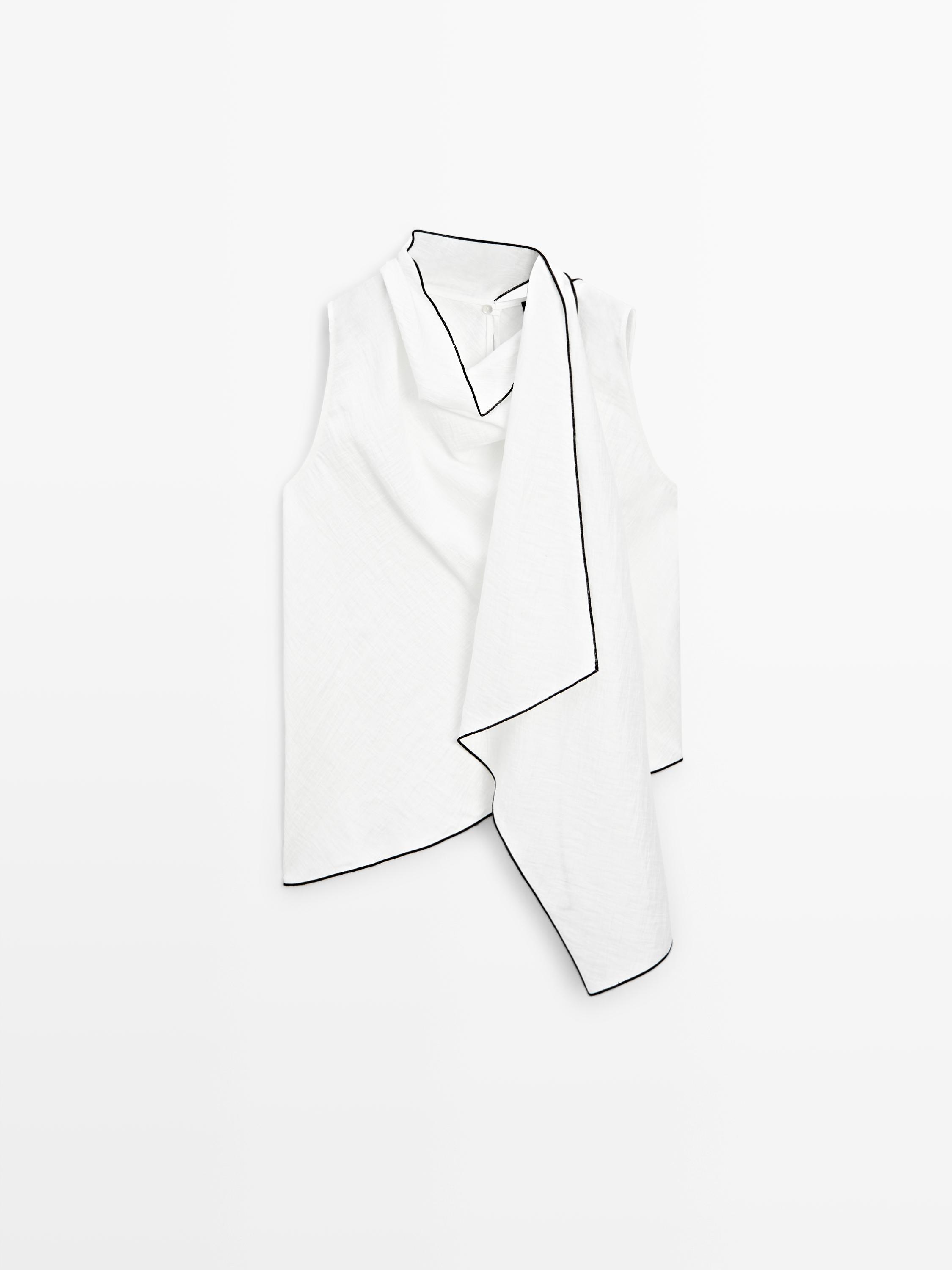 Dökümlü yakalı ve siyah biyeli, kolsuz beyaz bluzun önden görünümü.