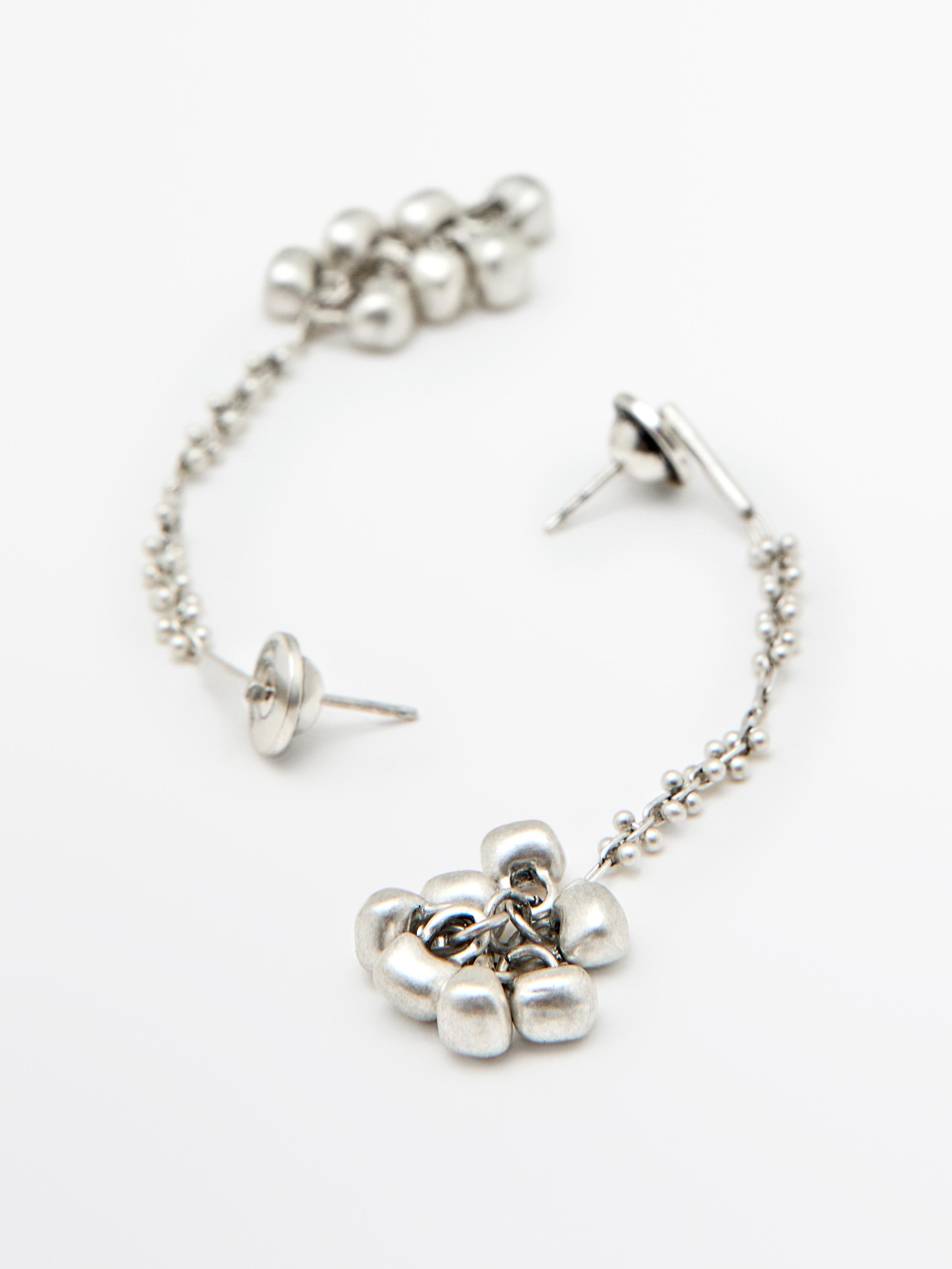 Lange, silberfarbene Ohrringe mit Gliederkette und abgerundeten Endstücken.