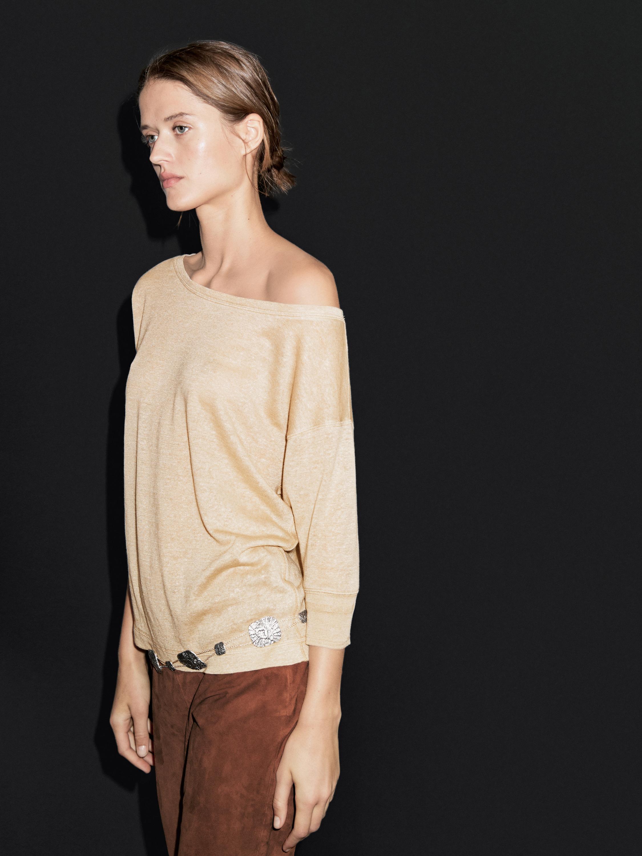 Beige long-sleeved off-the-shoulder top and hem detail set, brown pants.