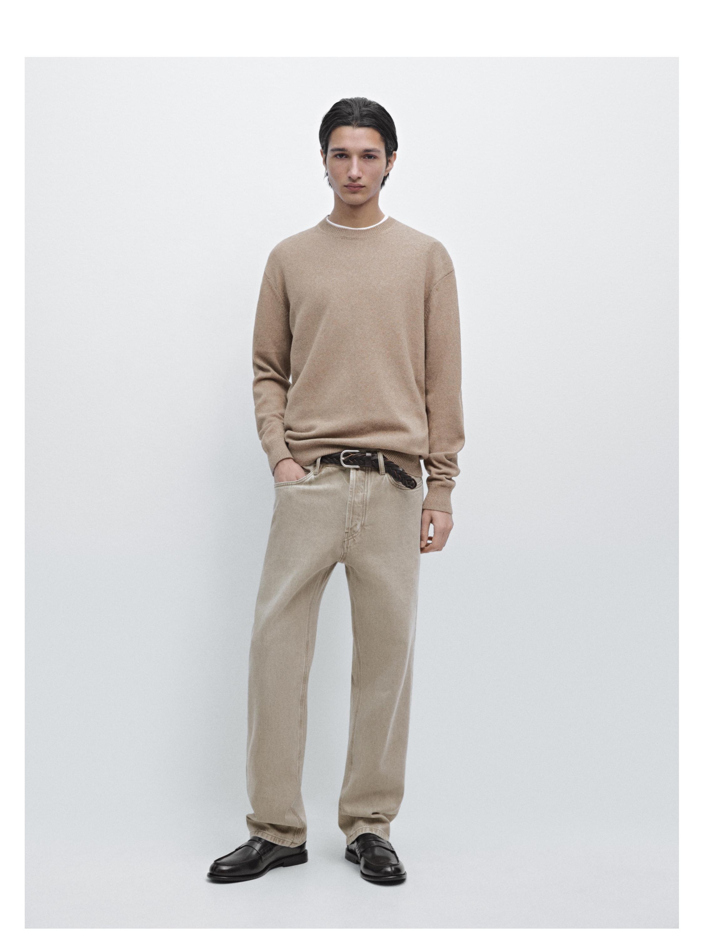 Sæt med beige langærmet sweater og lige grågrønne jeans med sidelommer, mørkt bælte og sorte sko.