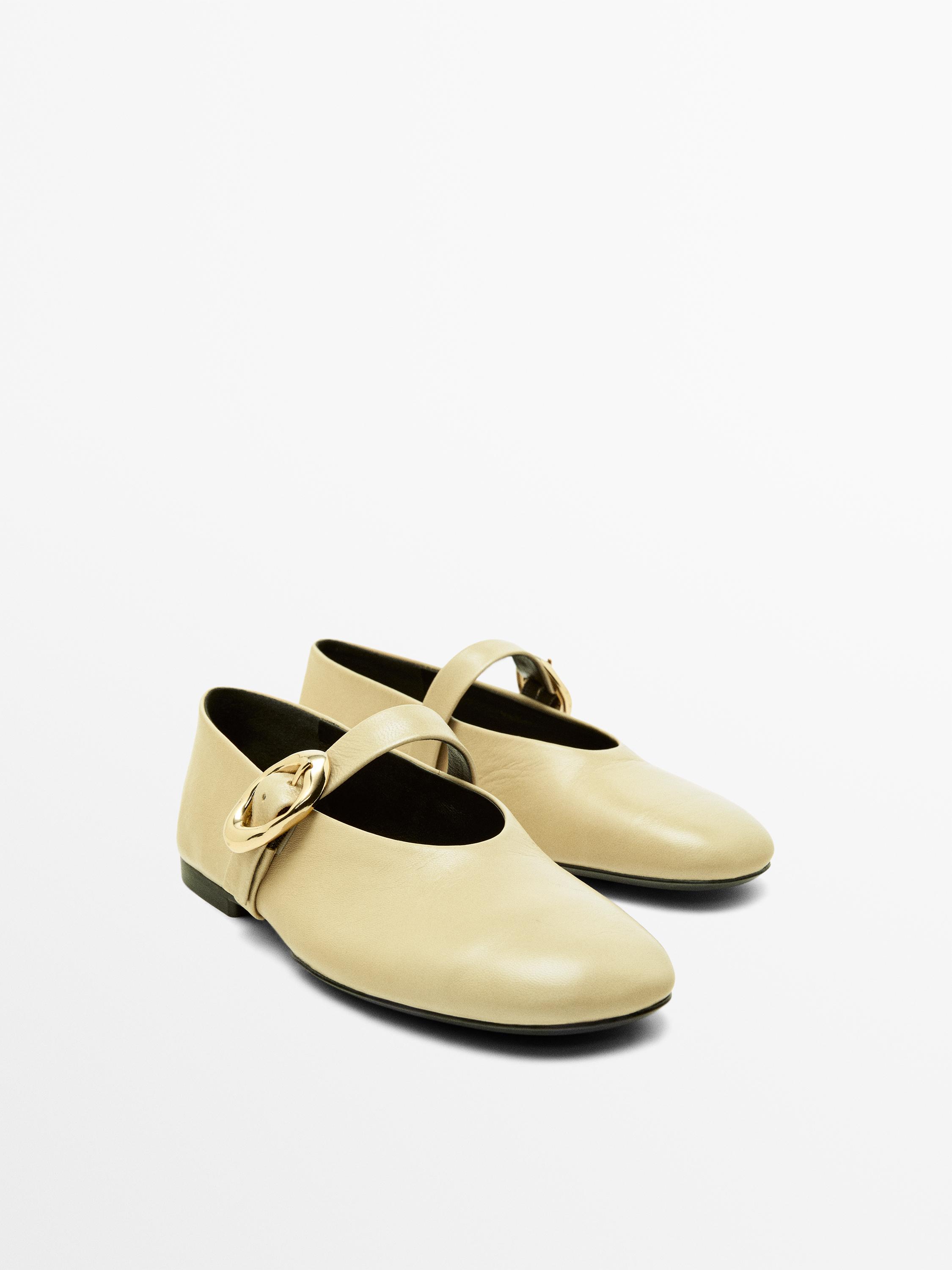 Vista frontal de bailarinas crudo con hebilla dorada y tira en el empeine.