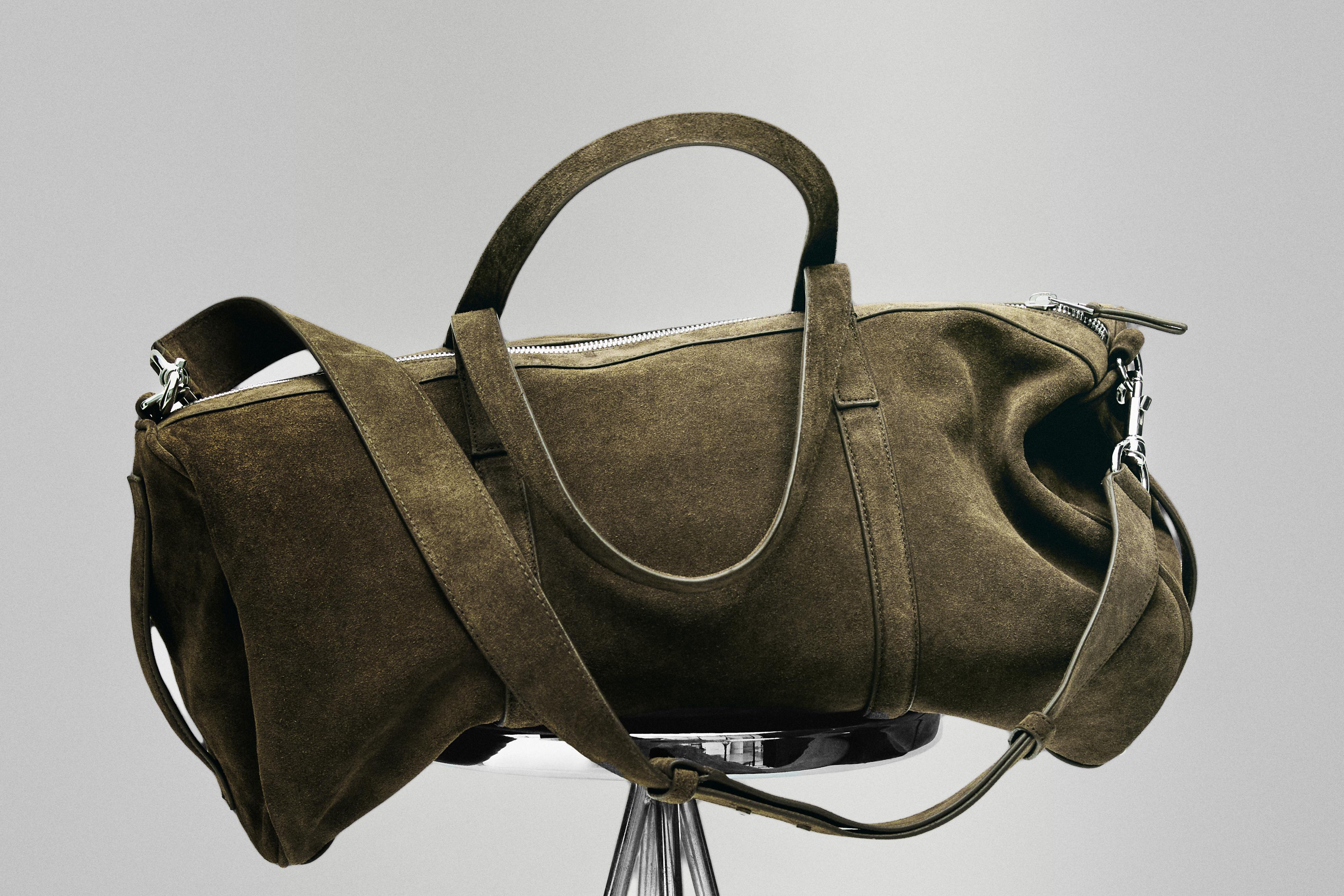 Bolso de viaje kaki con asas dobles y correa ajustable, cierre de cremallera y diseño espacioso.