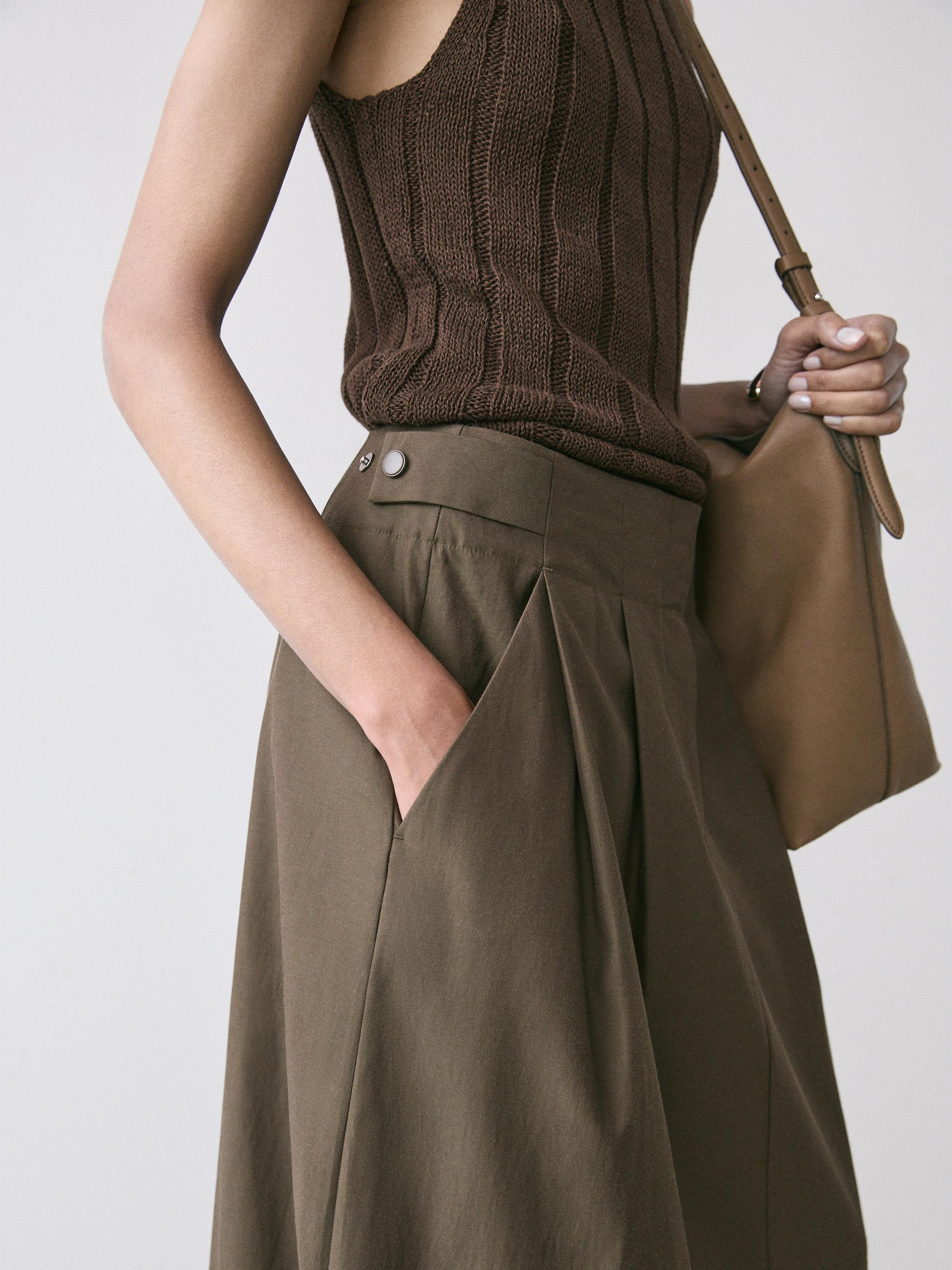 Kaki koloreko gona midi tolestu eta alboetako poltsikoekin, puntu marroiko top batekin konbinatuta.