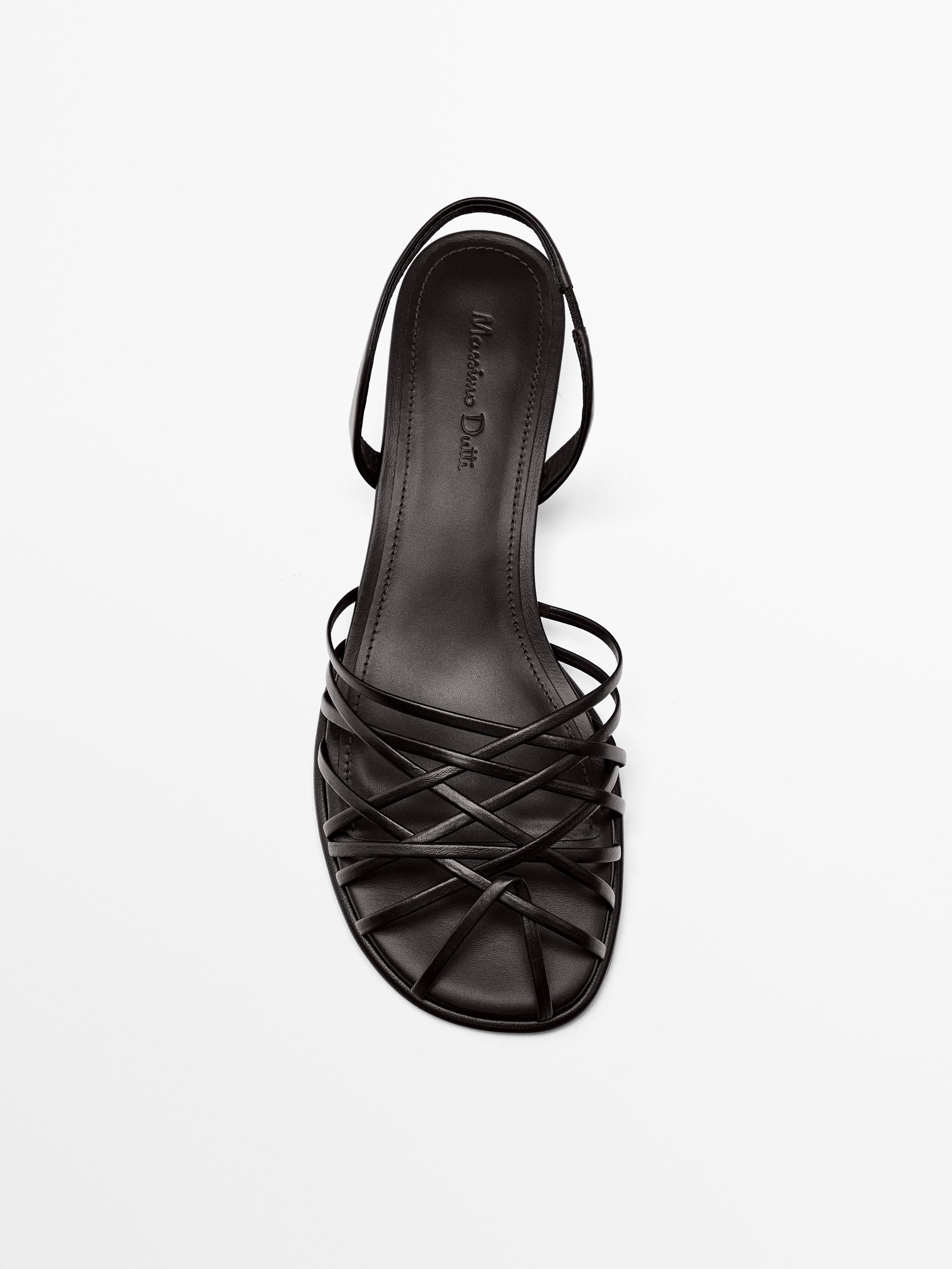 منظر أمامي لصندل أسود بسيور متقاطعة وشعار على النعل الداخلي