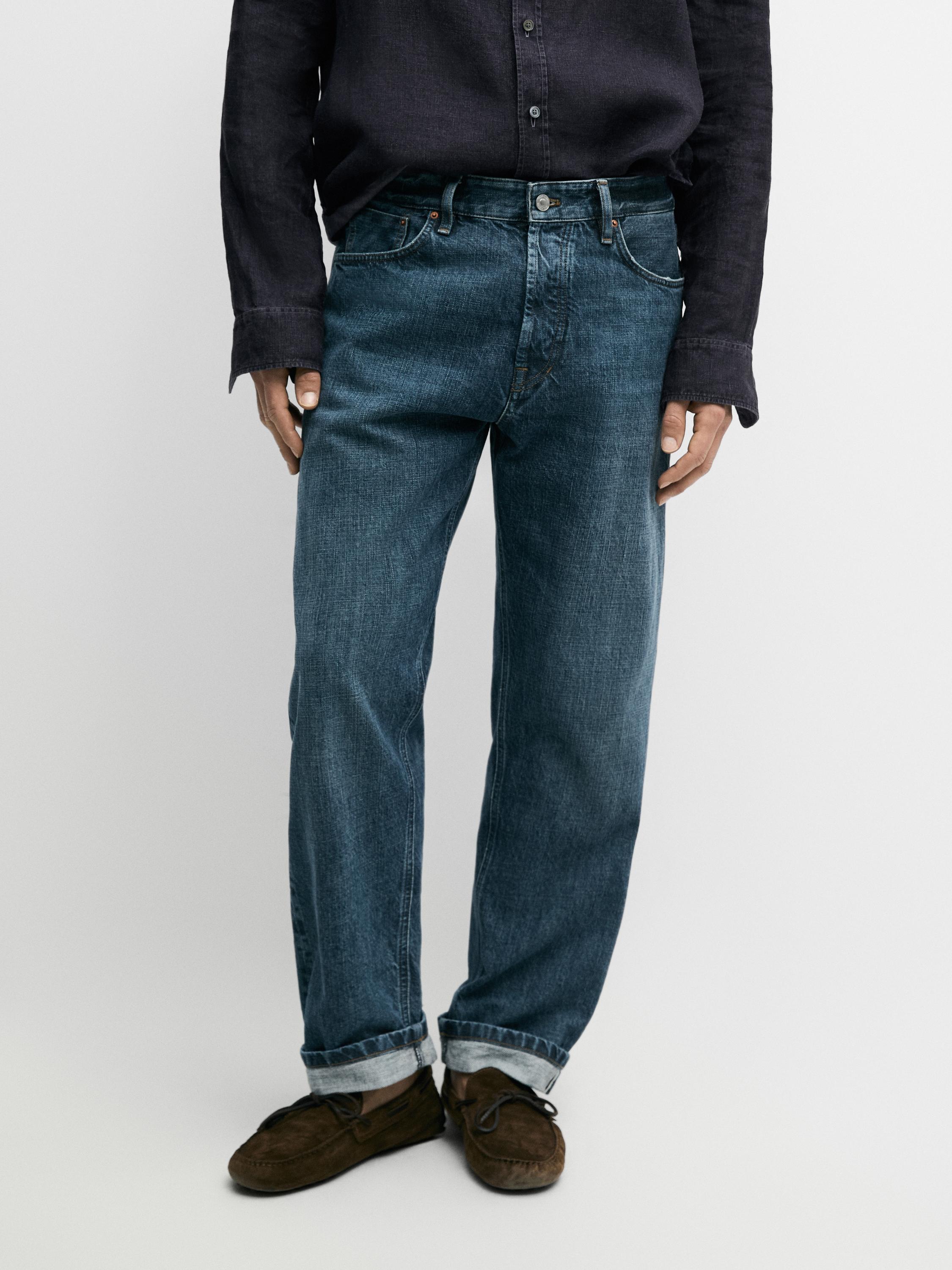 Conjunto de jeans índigo retos com bolsos frontais e traseiros visíveis, bainha virada.