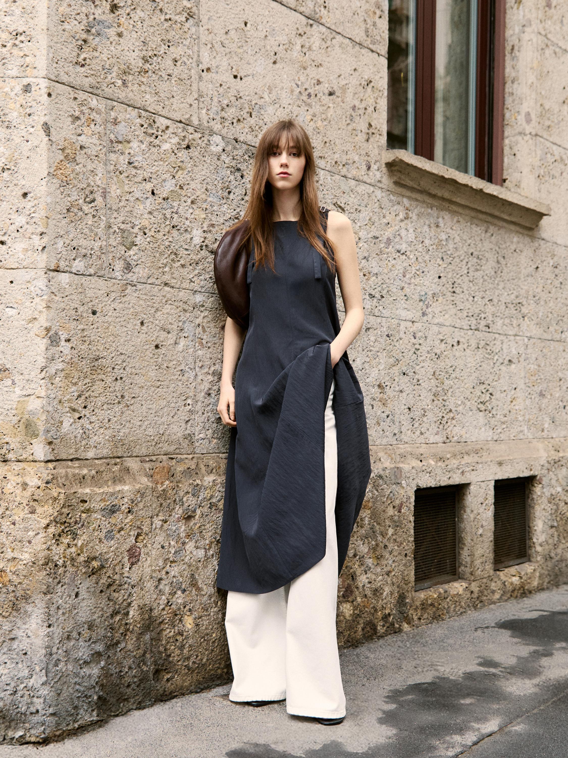 Ensemble asymétrique sans manches robe noire et pantalon large blanc.