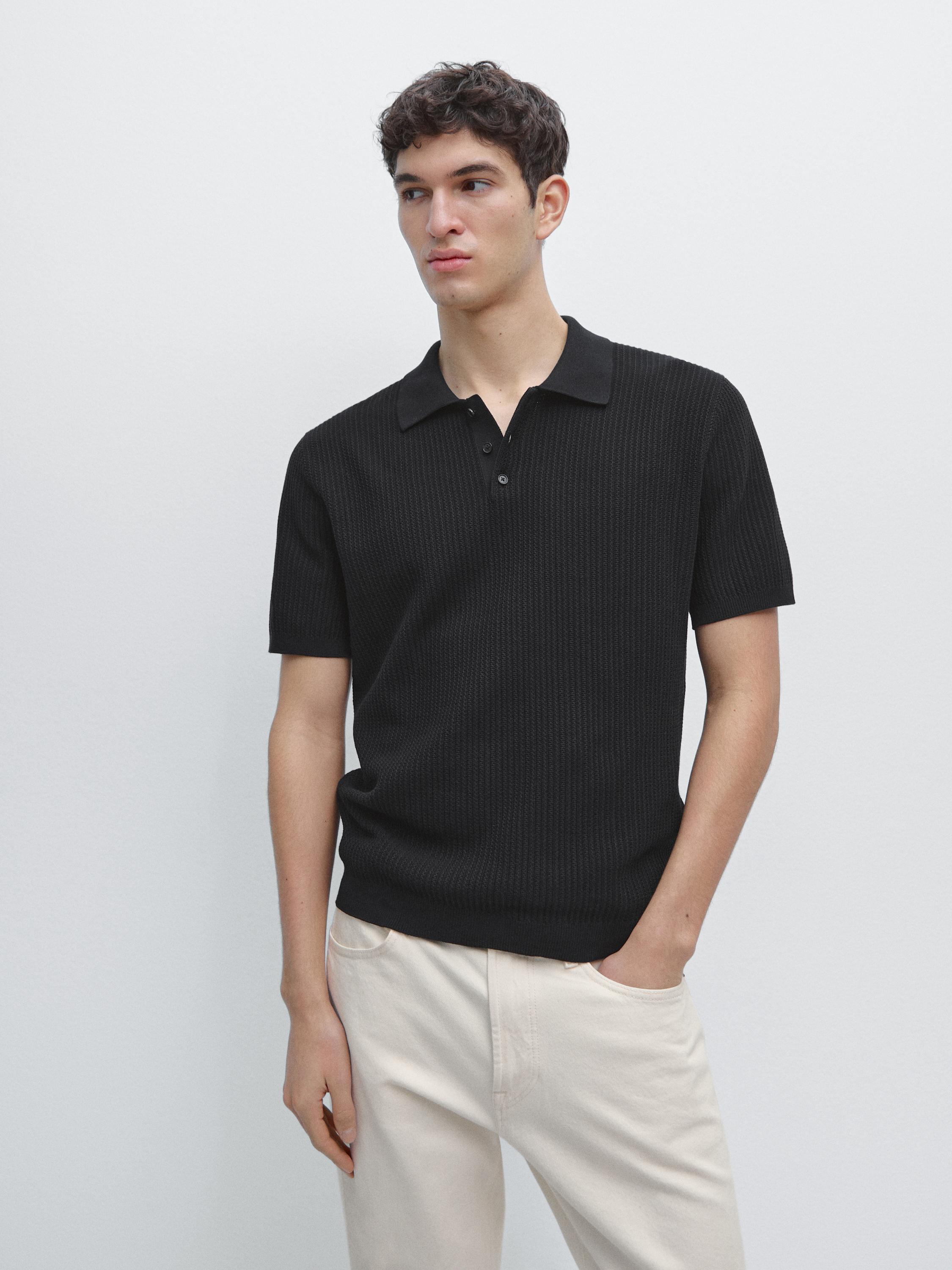 Ensemble polo noir en maille à manches courtes et col classique, combiné à un pantalon clair.